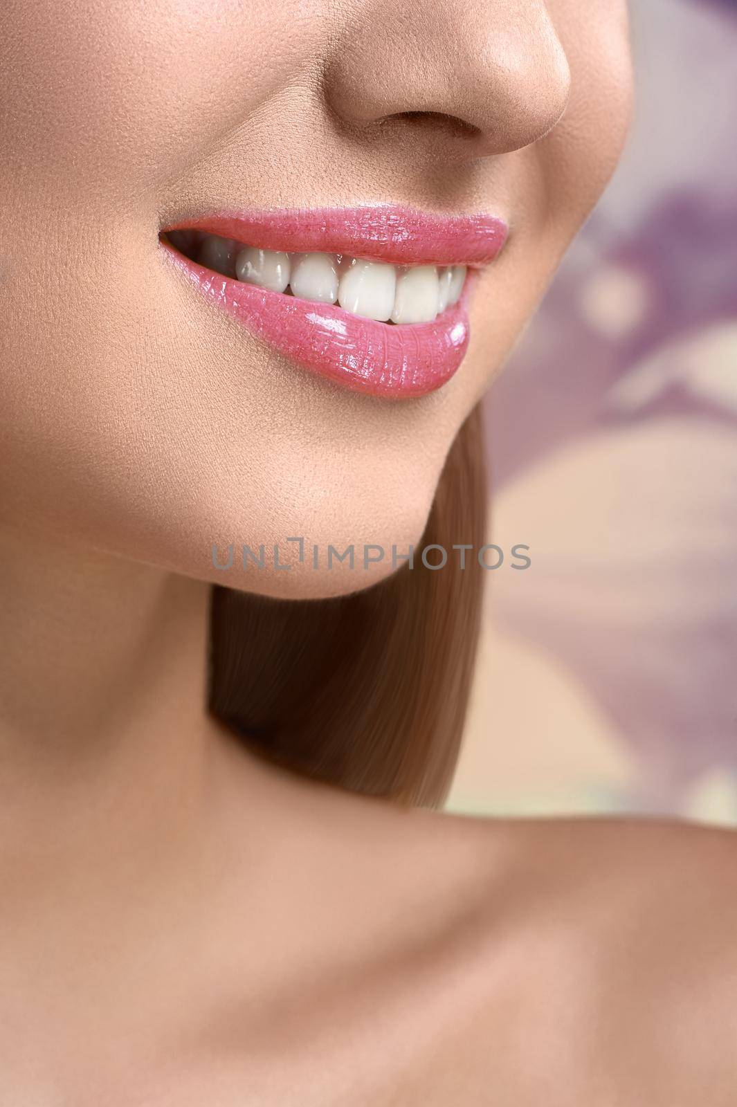 Glossy smile. Vertical close up of a perfect white healthy smile of a woman with beautiful teeth and full lips covered in pink lip gloss cosmetology beautician treatment products advertising concept
