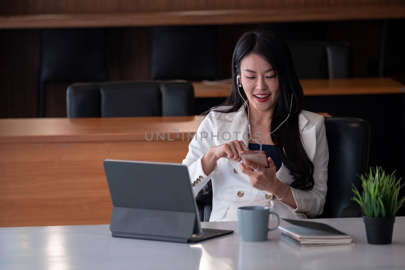 Happy of smiling businesswoman working with computer tablet and listen music on earphone.