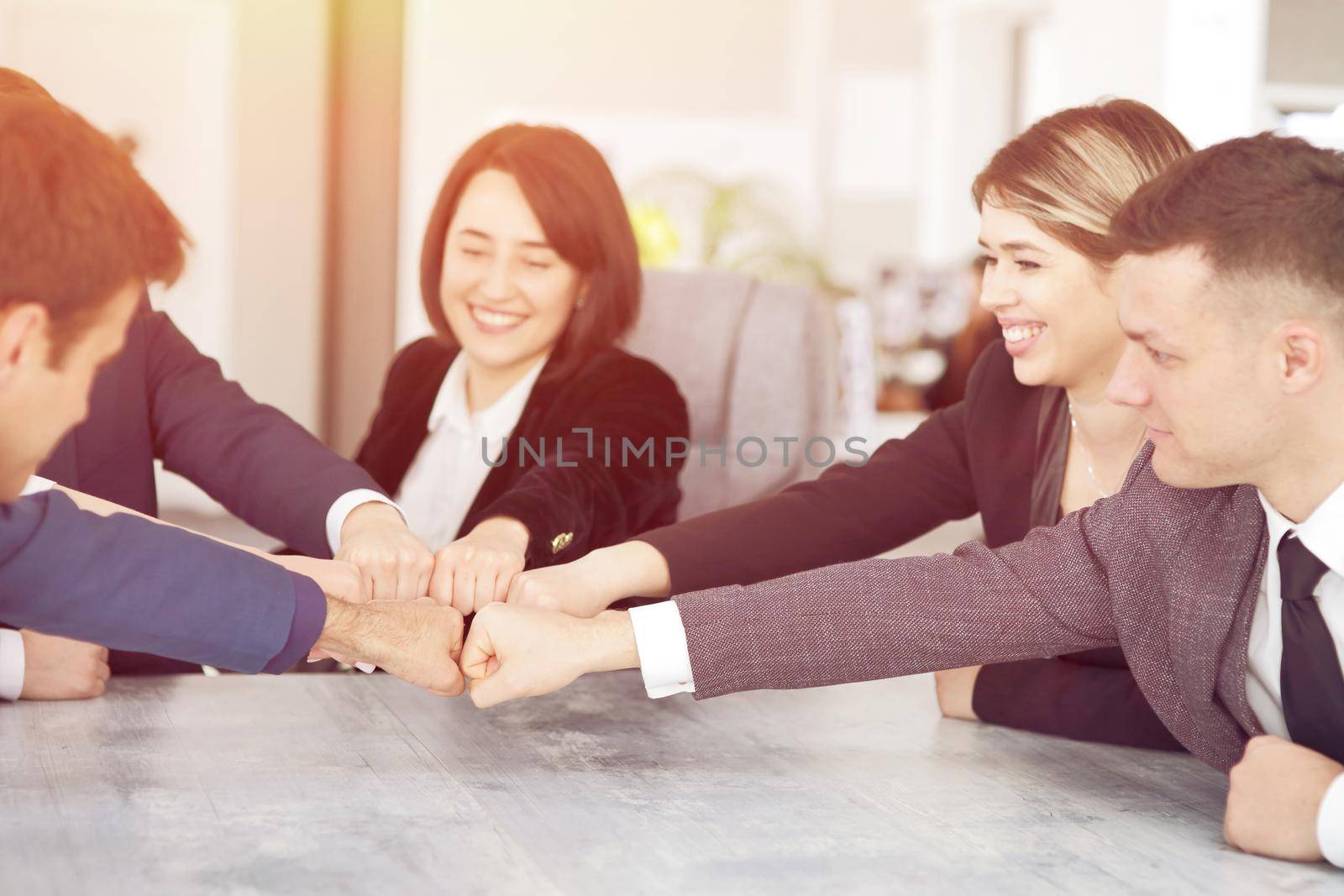 Unity and teamwork concept of young business people folding their hands together by selinsmo