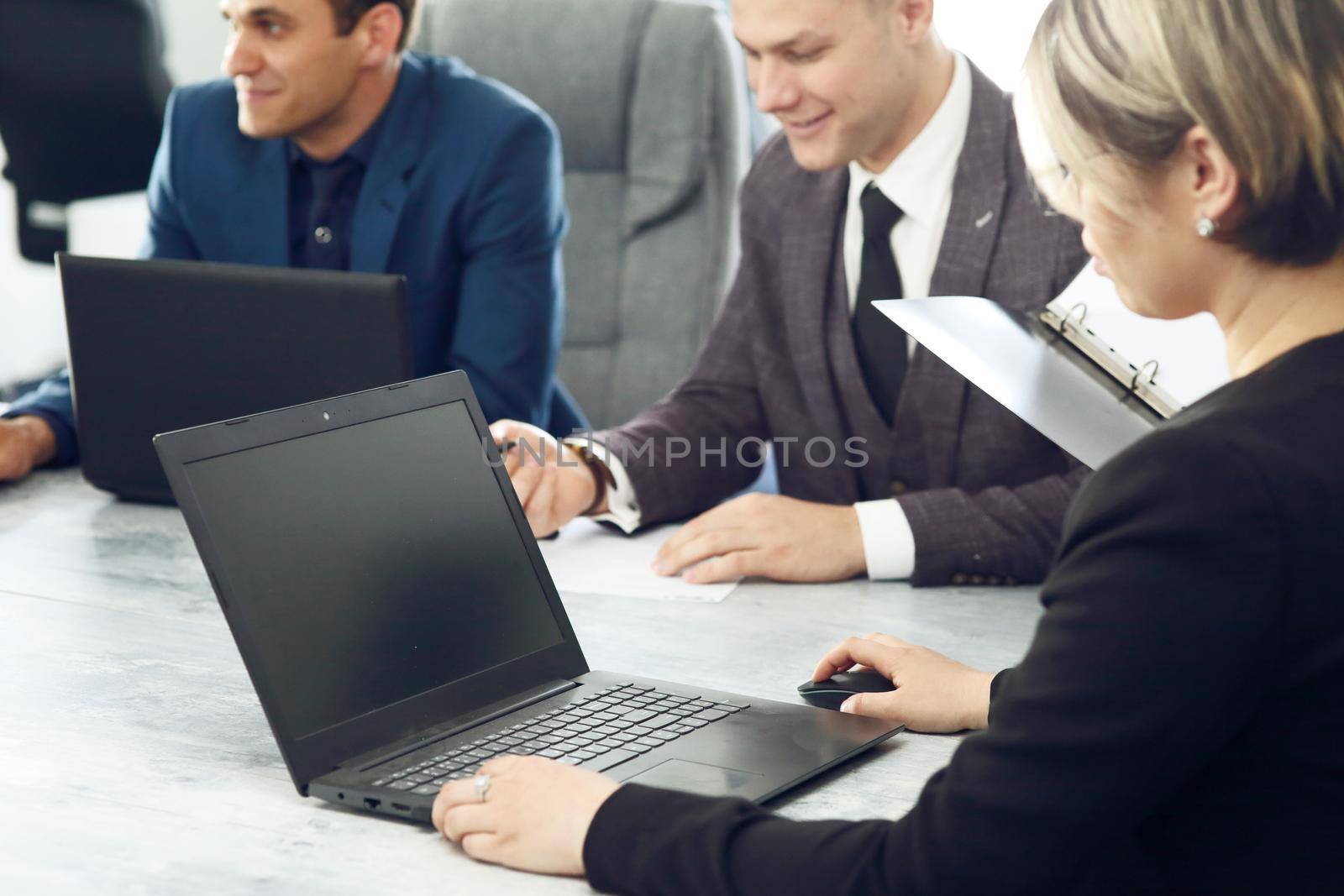 Laptop against the background of a group of young business people in the office discussing a work idea together. 
