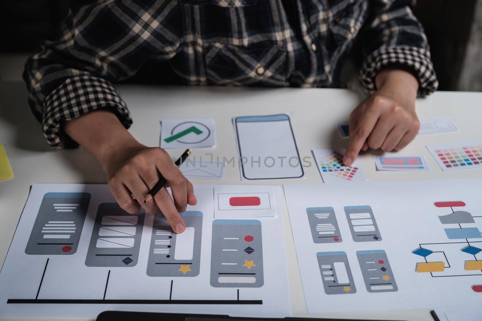 Closeup of male ux developer and ui designer about mobile phone app interface in living room at home. Creative digital development agency concept