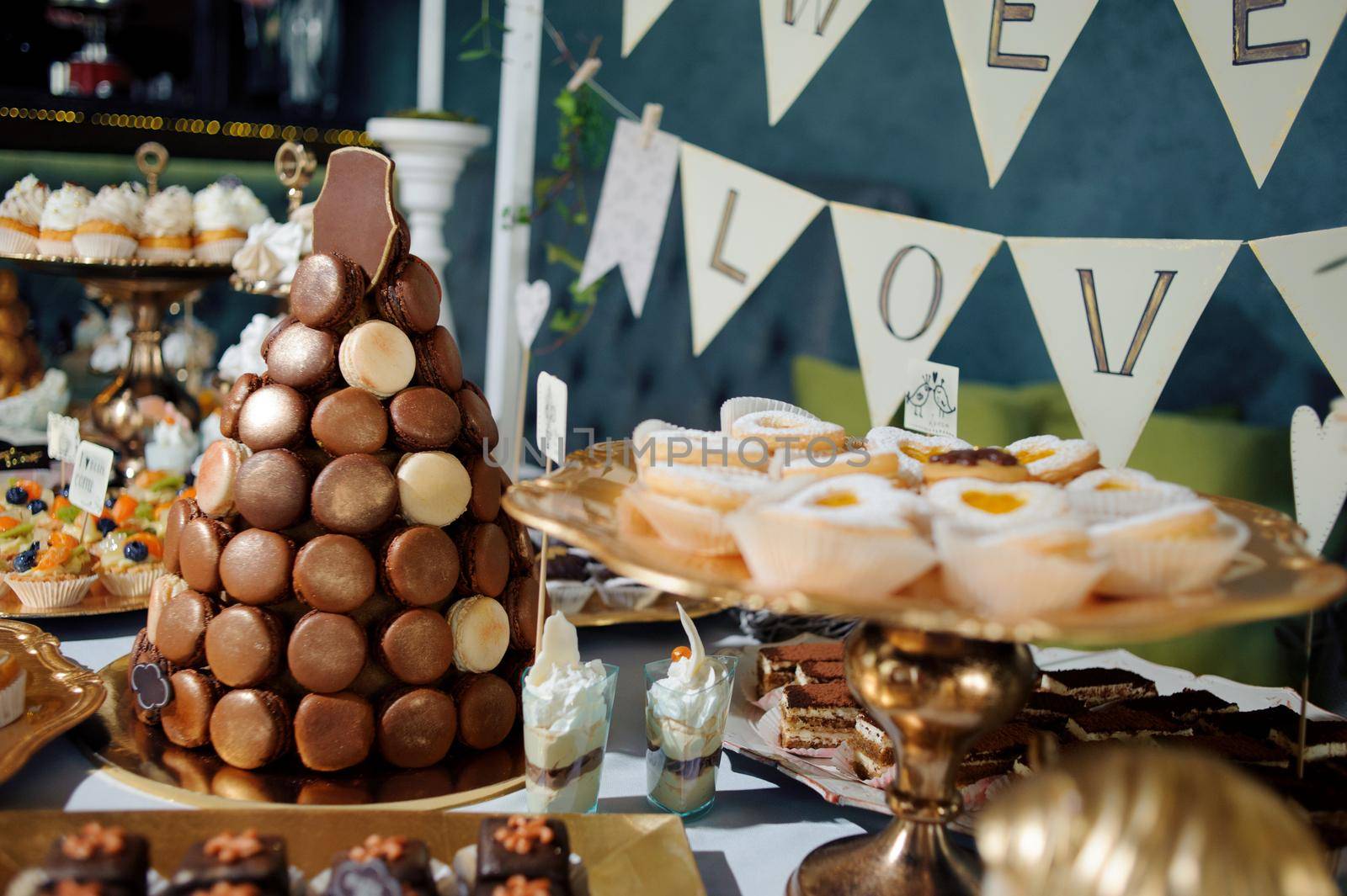 dressing table with sweets, candy pyramid decorated with orange butterflies, cupcakes on a tray, festive table with desserts.