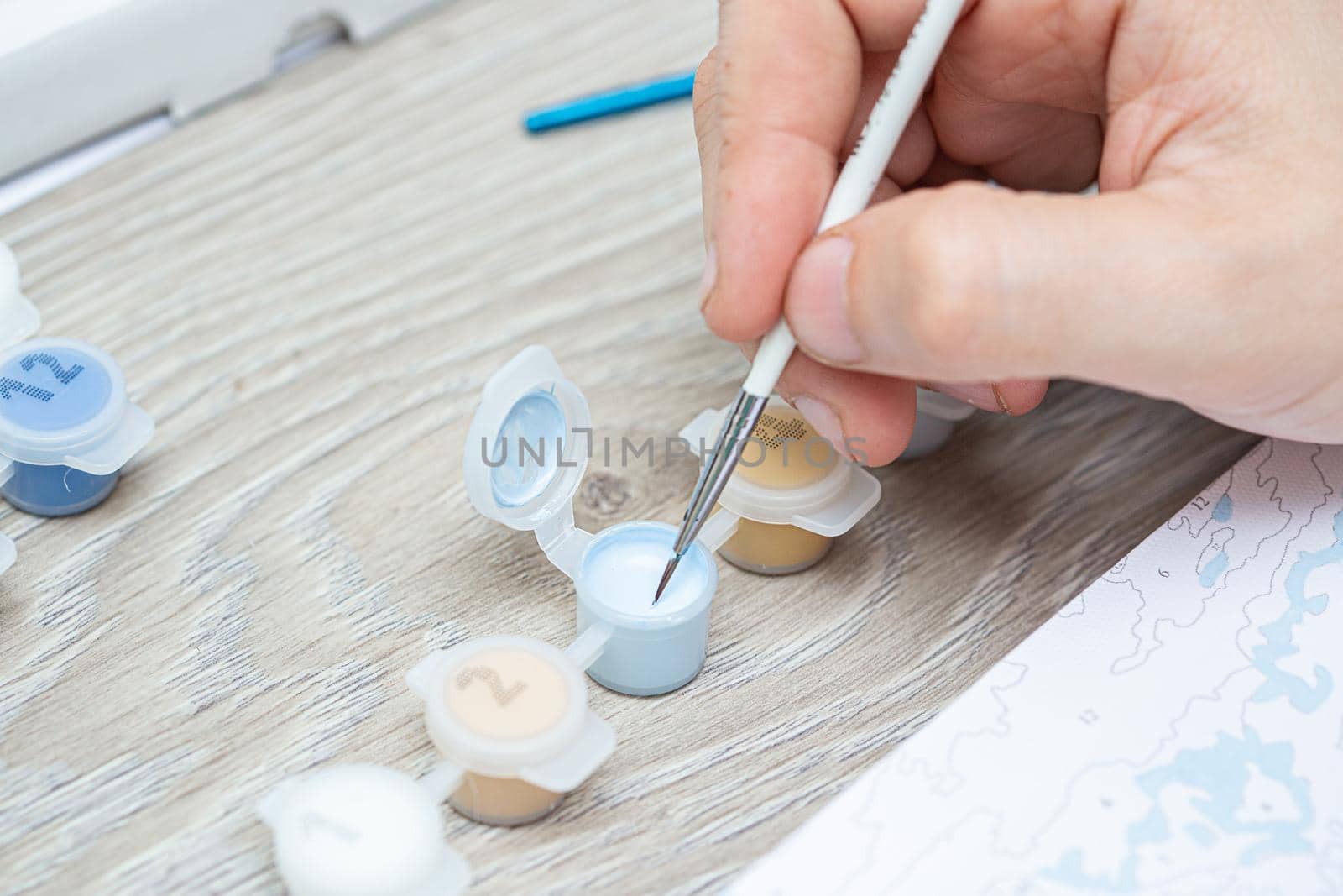 A mans hand holding a brush for drawing close-up. Painting for beginners.Closeup, selective focus.