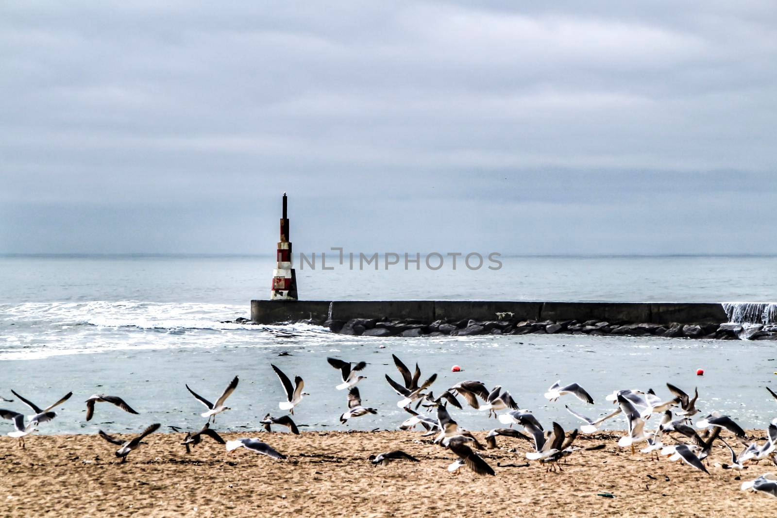 Breakwater and lighthouse in a cloudy day of Aguda Beach, Miramar, Arcozelos town