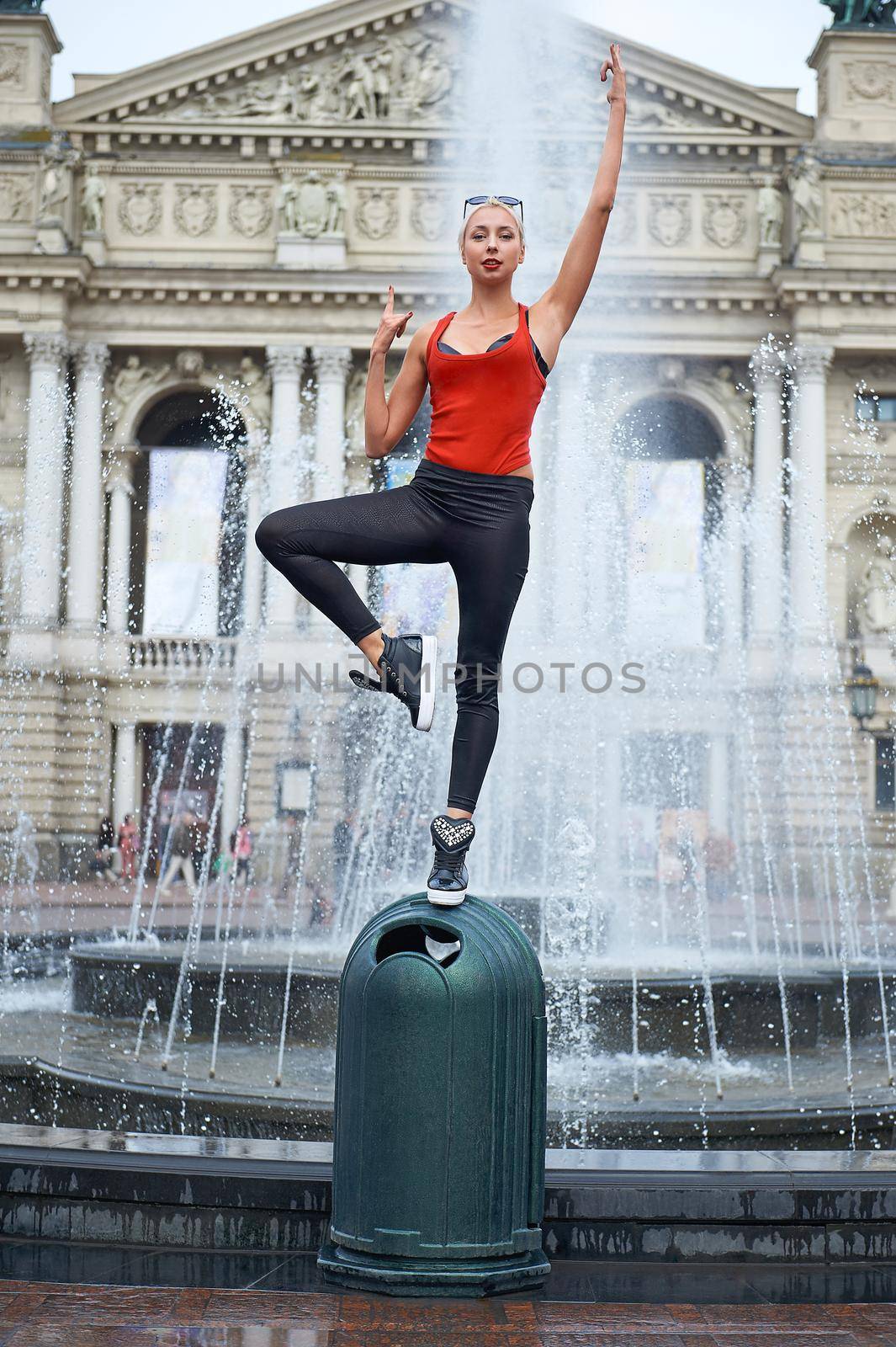 Shot of a young beautiful female hip-hop dancer balancing on one foot posing near the fountain at the city center performing outdoors.