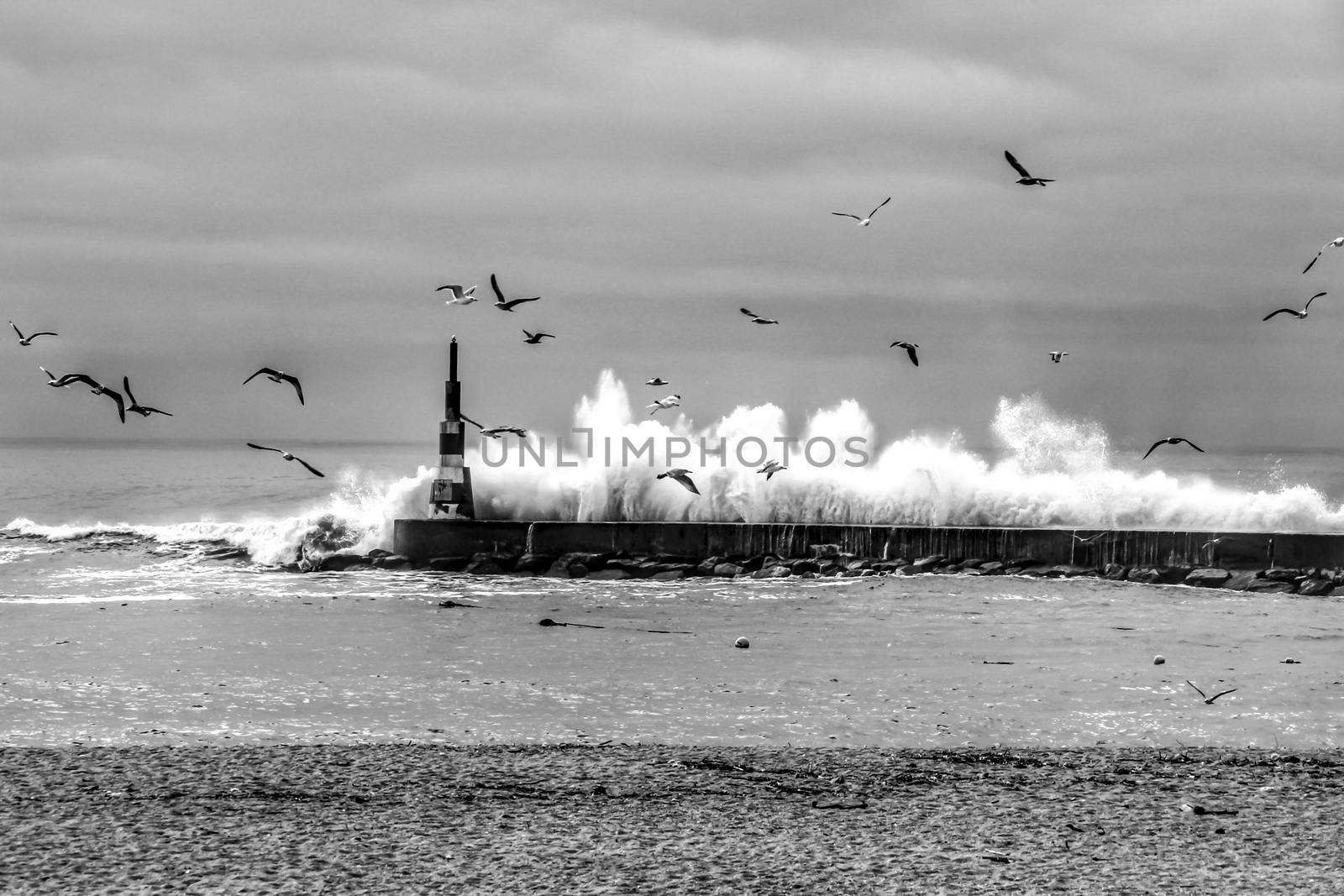 Giant waves breaking on the breakwater and the lighthouse on Aguda Beach, Miramar, Arcozelos town