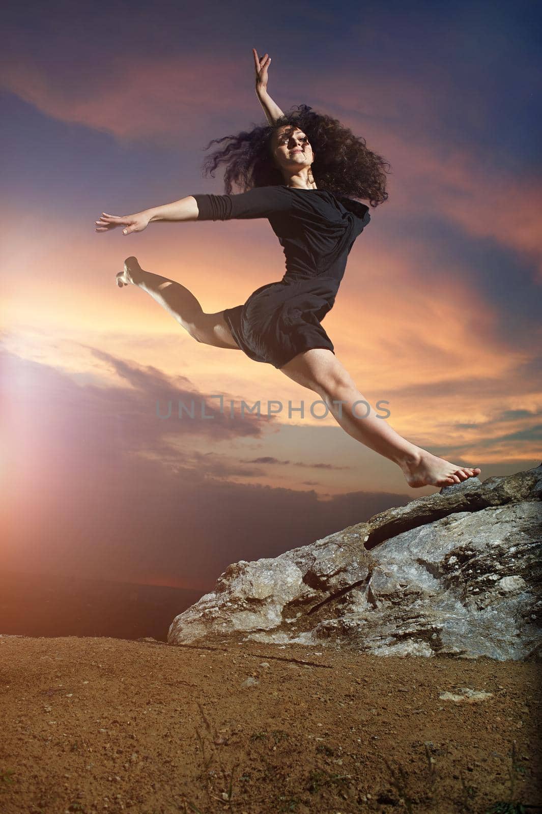 beautiful, flexible, young, curly dancing girl - performs split in the mountains on the wonderful mountain landscape at sunrise.
