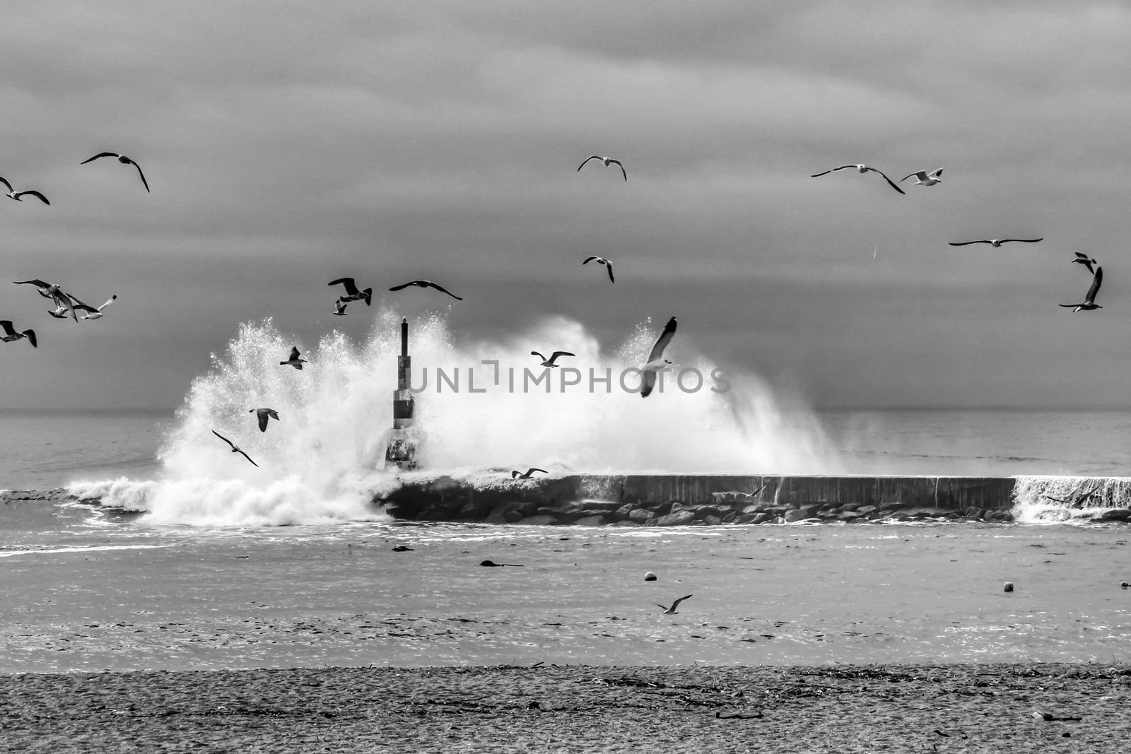 Giant waves breaking on the breakwater and the lighthouse on Aguda Beach, Miramar, Arcozelos town