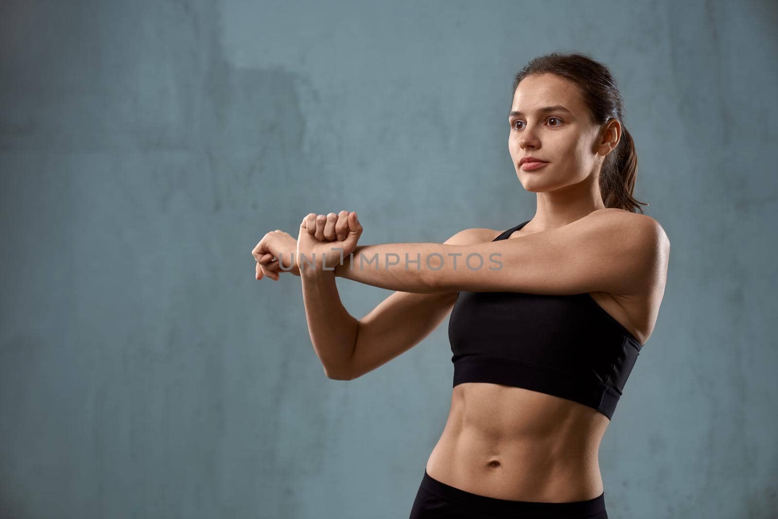 Flexible fitnesswoman stretching arm before training. by SerhiiBobyk