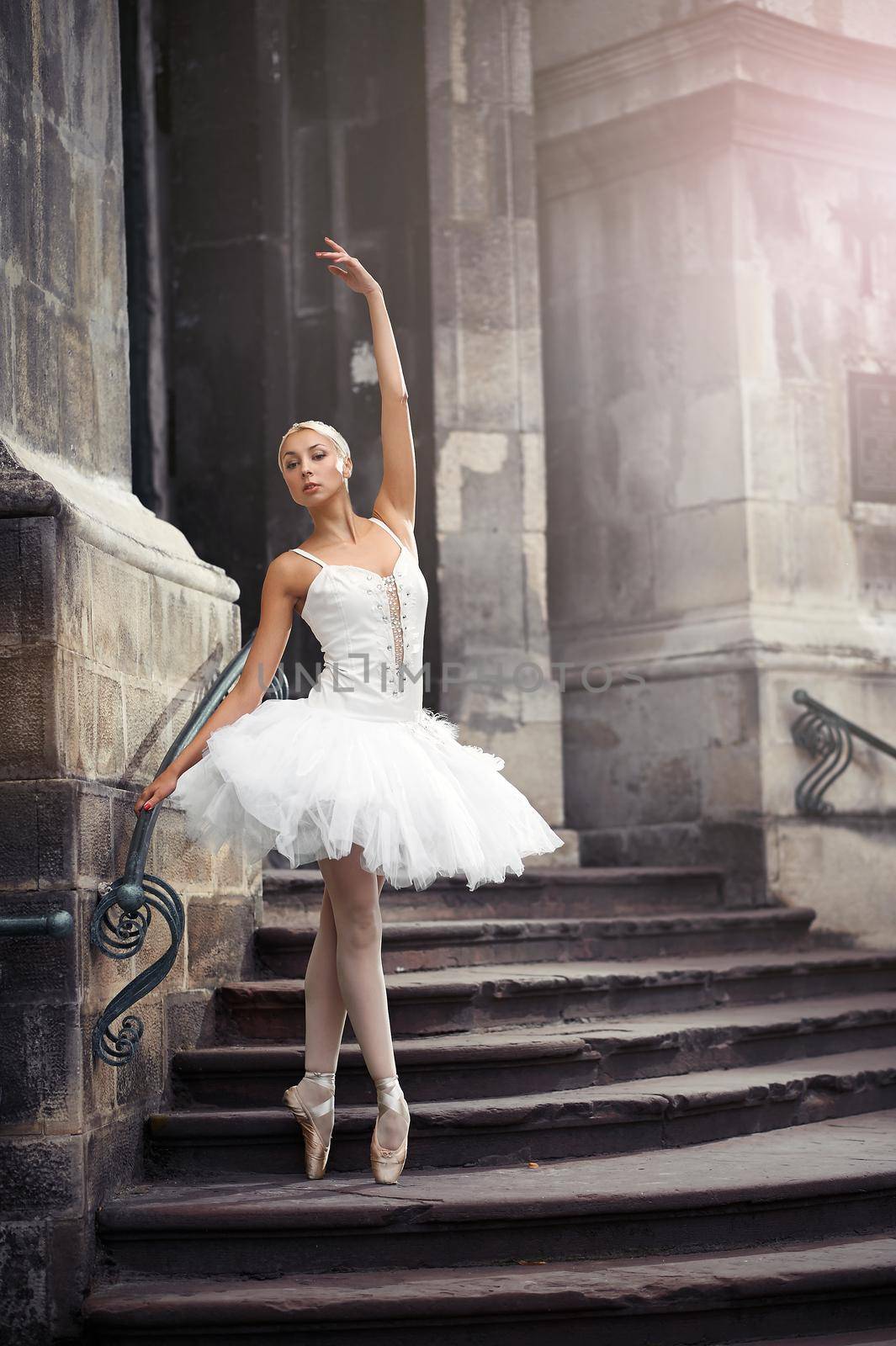 Catching last sun beams. Portrait of a ballerina performing outdoors near an old building