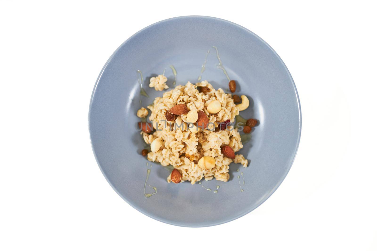 Top view of tasty and appetizing oatmeal with dried fruits and raisins,nuts on white background. Concept of delicious and healthy porridge for maintain body weight or emaciation. 