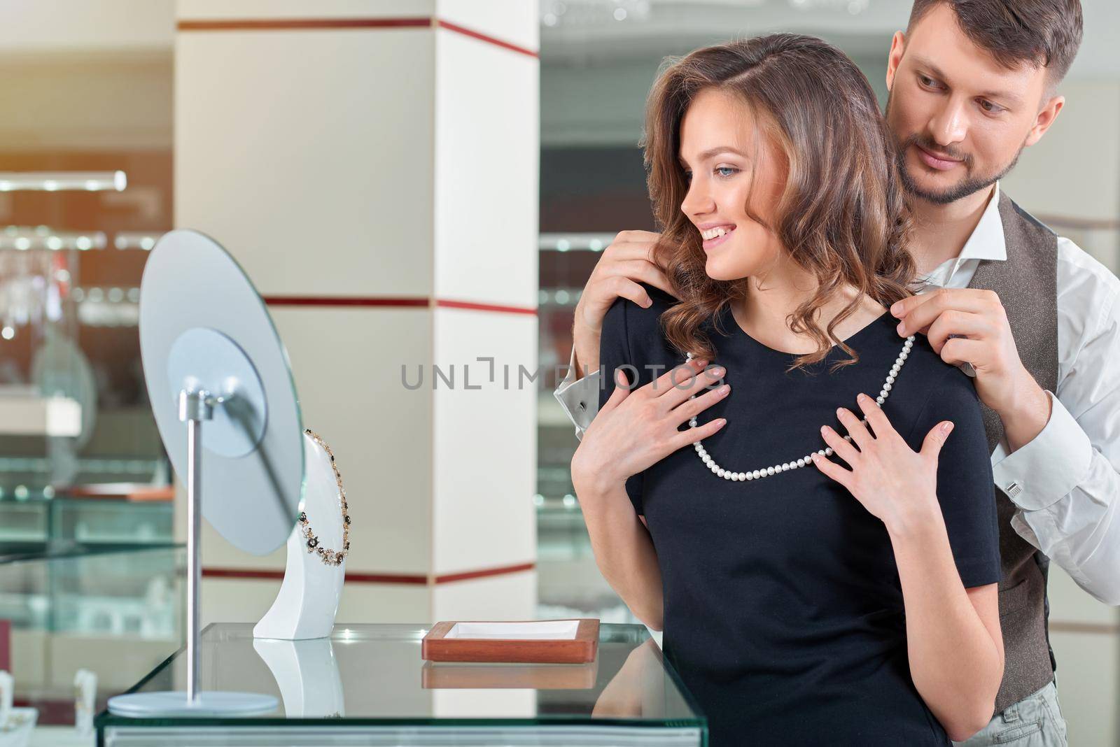 You look gorgeous Happy young couple trying on a pearl necklace at the jewelry store cpyspace anniversary sale shopping buying consumerism wealthy wellbeing people customers love couple concept.