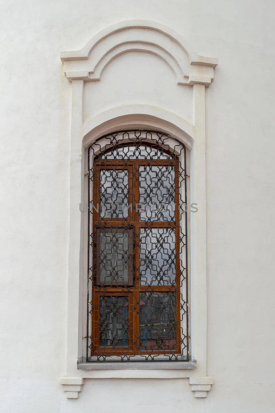 A window with a beautiful grille in the old Orthodox church. Outdoors, building fasade front view. by Essffes