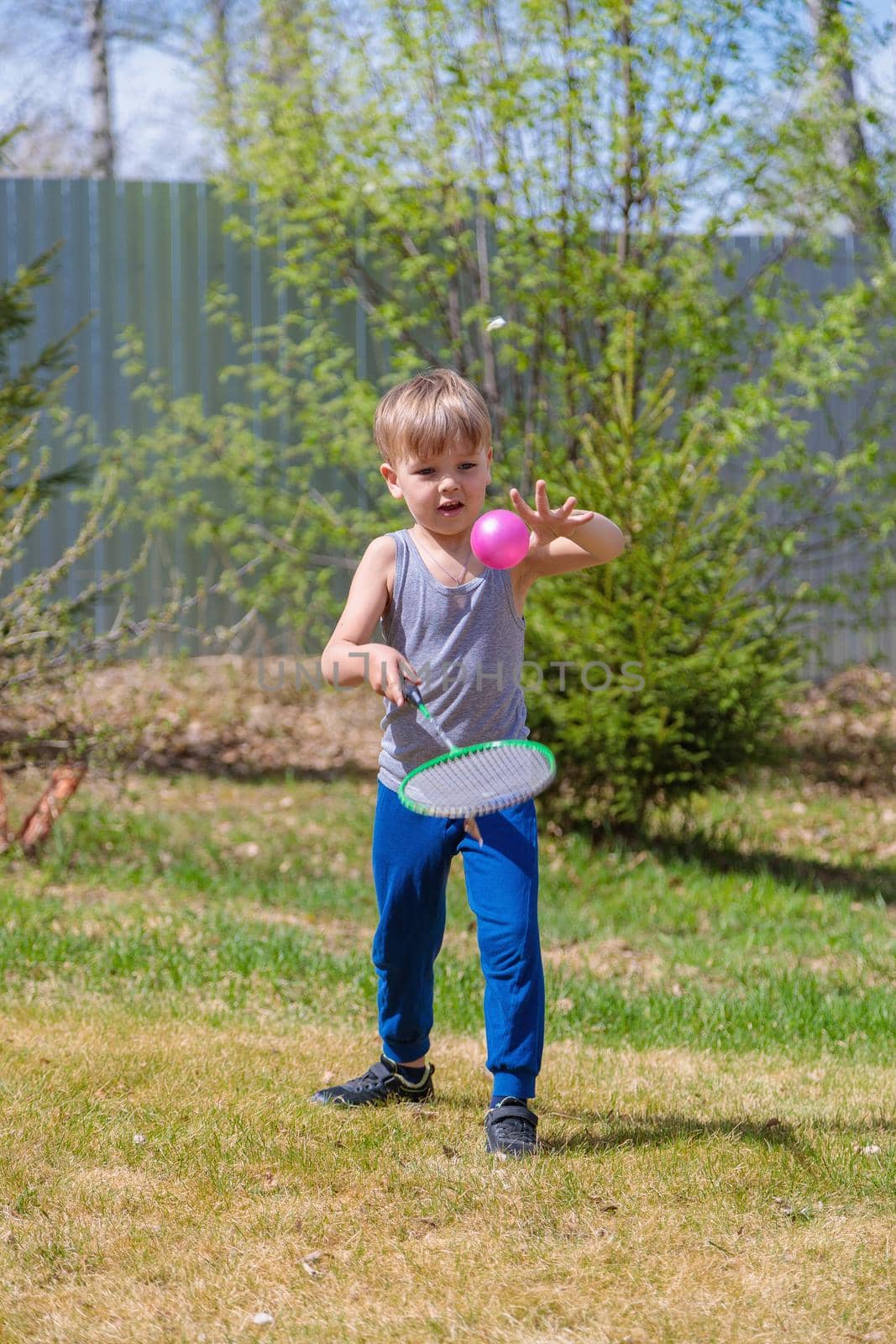 A fair-haired child plays badbinton on the lawn by Yurich32