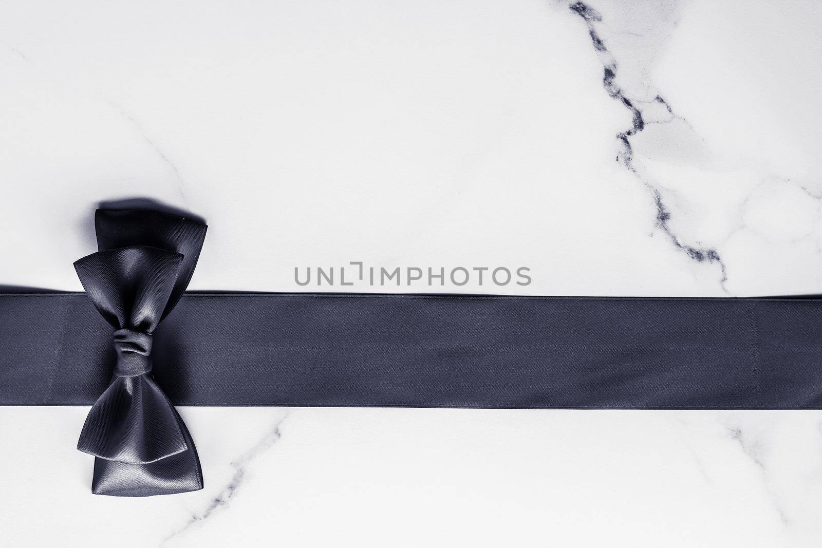 Holiday gift, decoration and sale promotion concept - Black silk ribbon and bow on marble background, flatlay