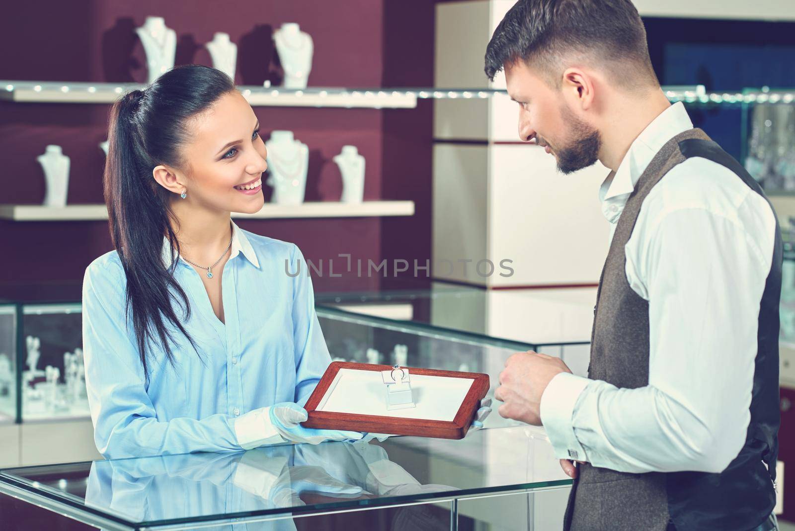 Help of a pro. Professional female jeweler smiling helping her male customer showing him diamond engagement ring to buy service helpful professional job occupation worker shopping people concept