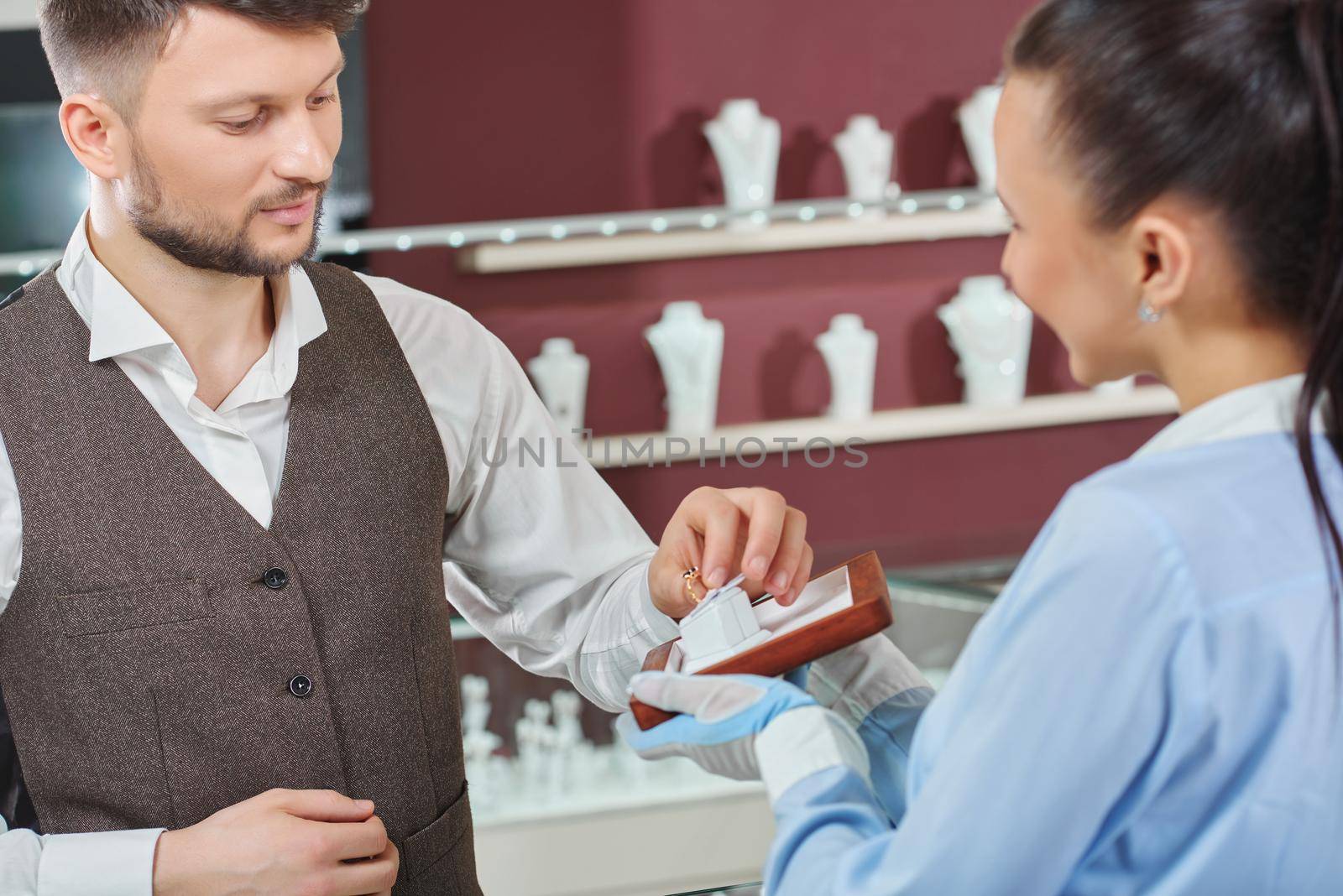 Helping to choose. Young man taking an engagement ring professional jeweler is showing him man buying jewelry at the store consumerism customer people sale discount shopping luxury fiance concept