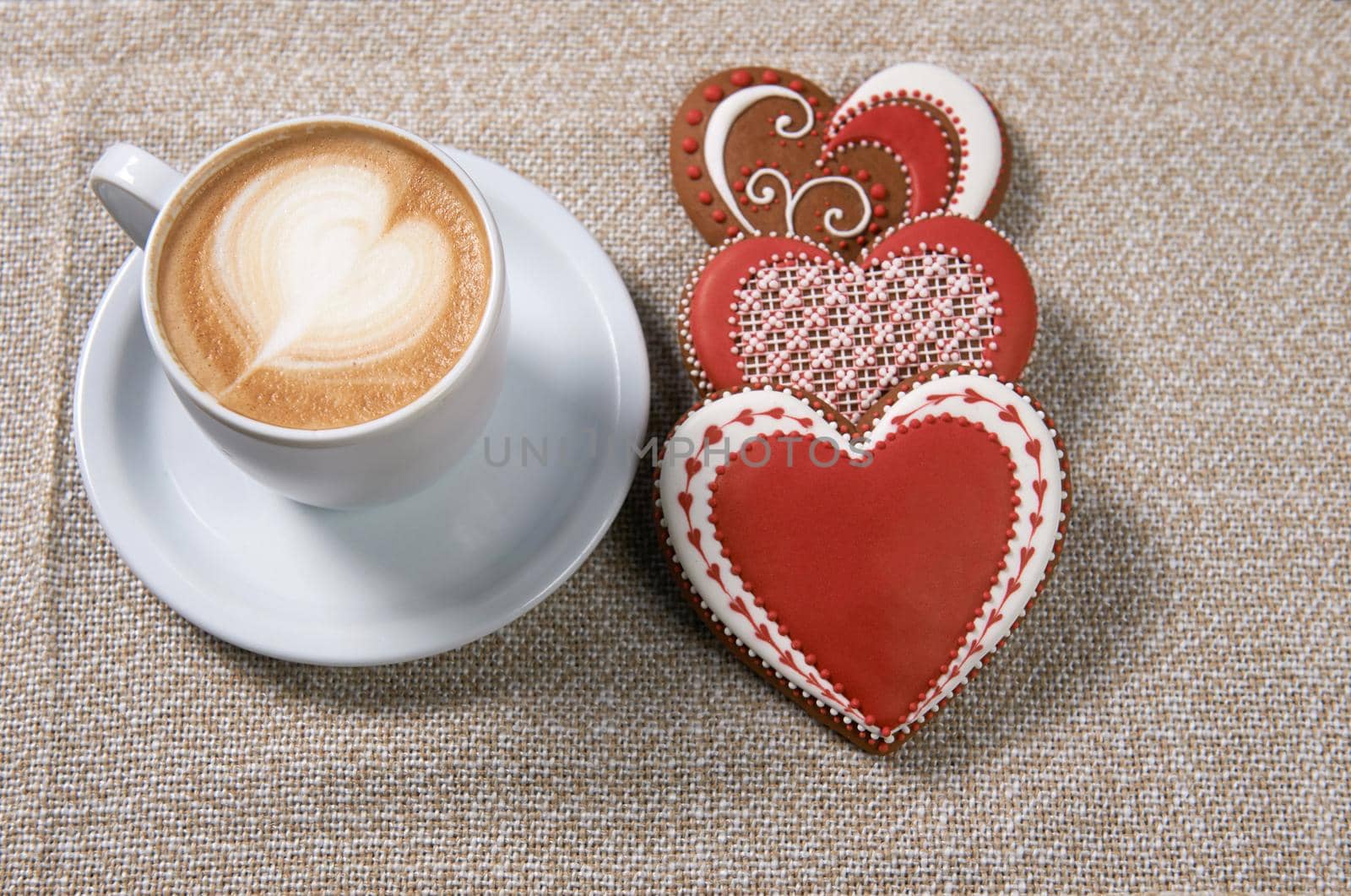 Morning love. Cup of coffee and three heart shaped cookies with glaze top view