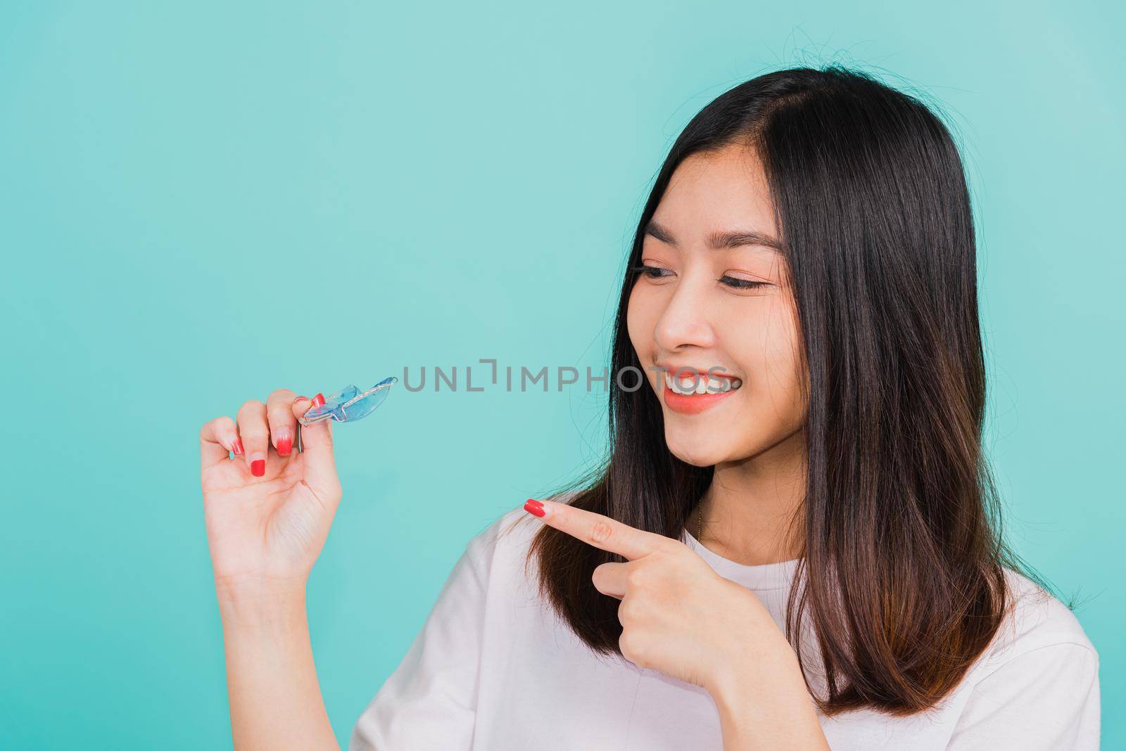 Portrait young Asian beautiful woman smiling pointing with finger silicone orthodontic retainers for teeth, Female hold teeth retaining tools after removable braces, Orthodontics dental care concept