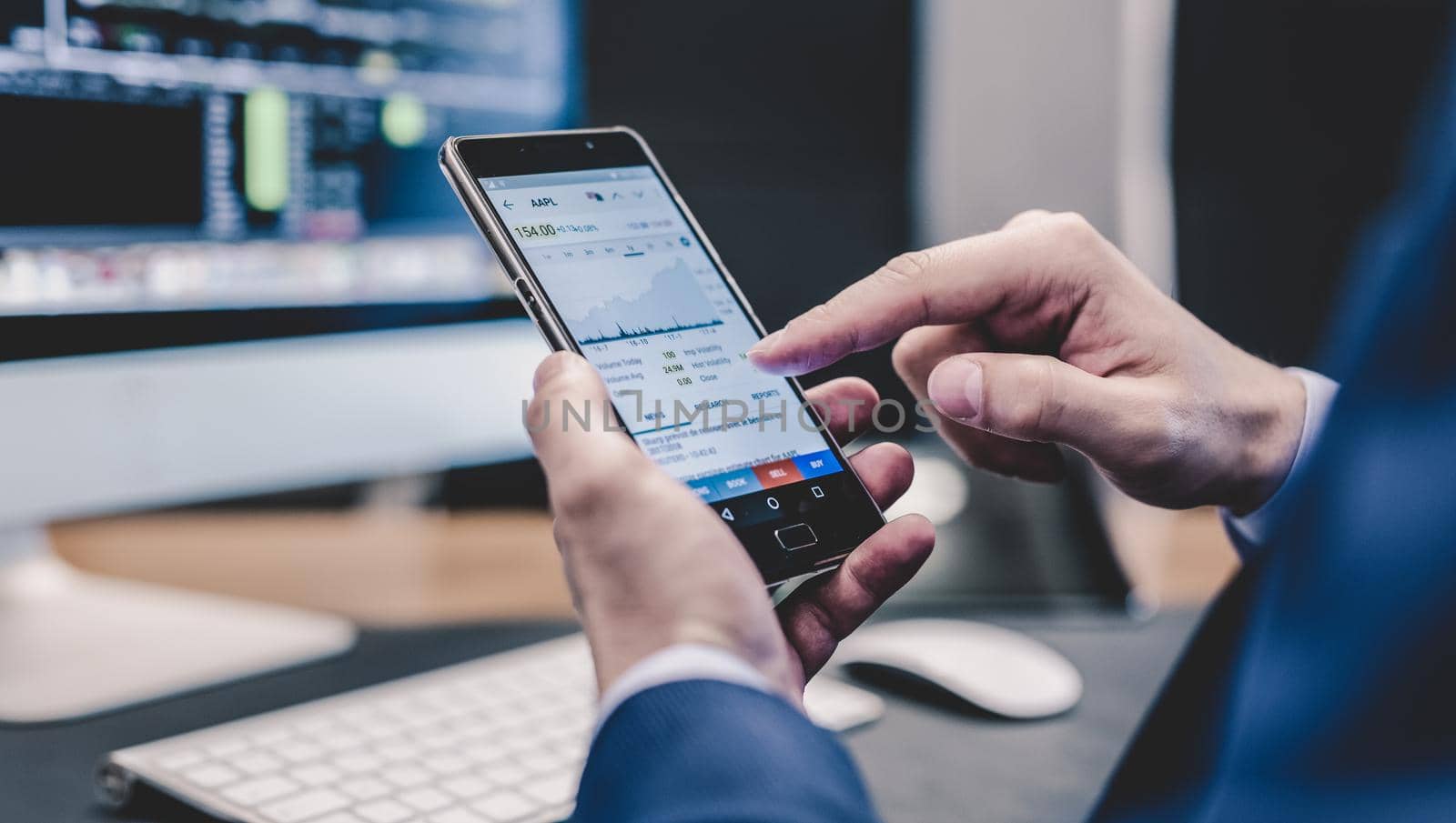 Close up of a businessman using smart phone in corporate office working space. Focus on mobile device.