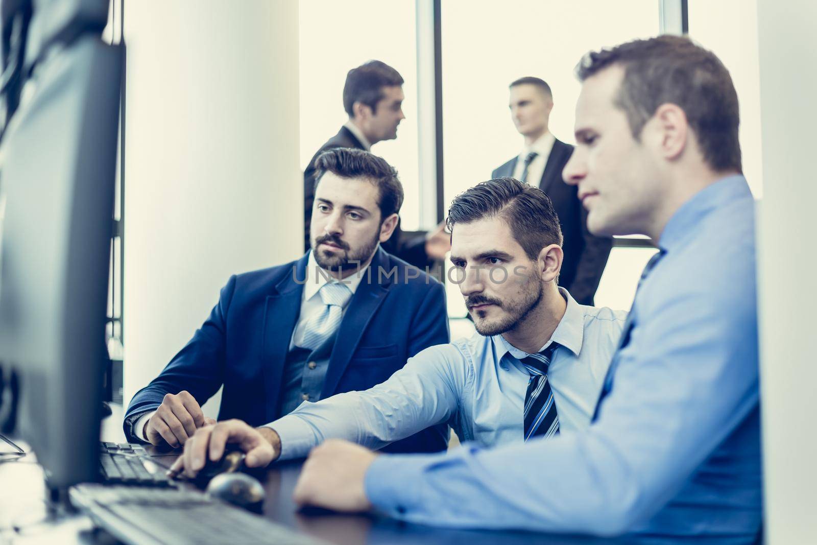 Business team working in corporate office. Businessmen trading stocks. Stock traders looking at graphs, indexes and numbers on multiple computer screens. Business success concept.