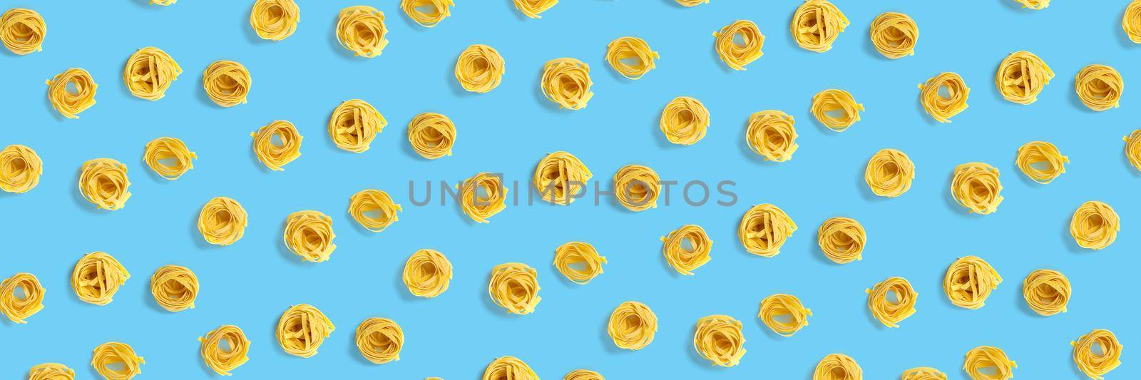 background from Italian tagliatelle pasta. raw pasta fettuccine, pop art background, flat lay. Italian raw nest pasta isolated on blue. not seamless pattern