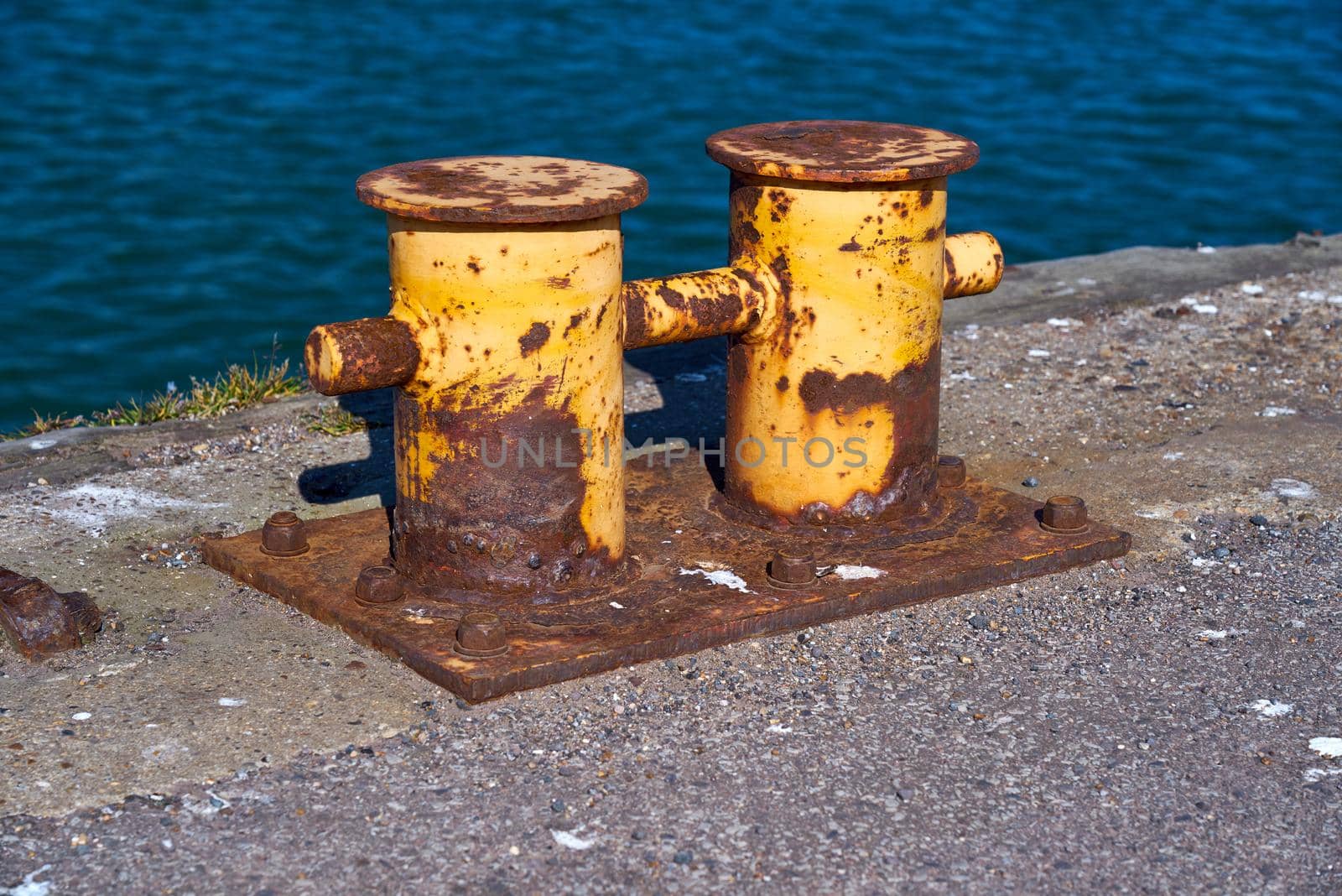 The rusty mooring bitt is used to secure boats and ships to a port or harbour.