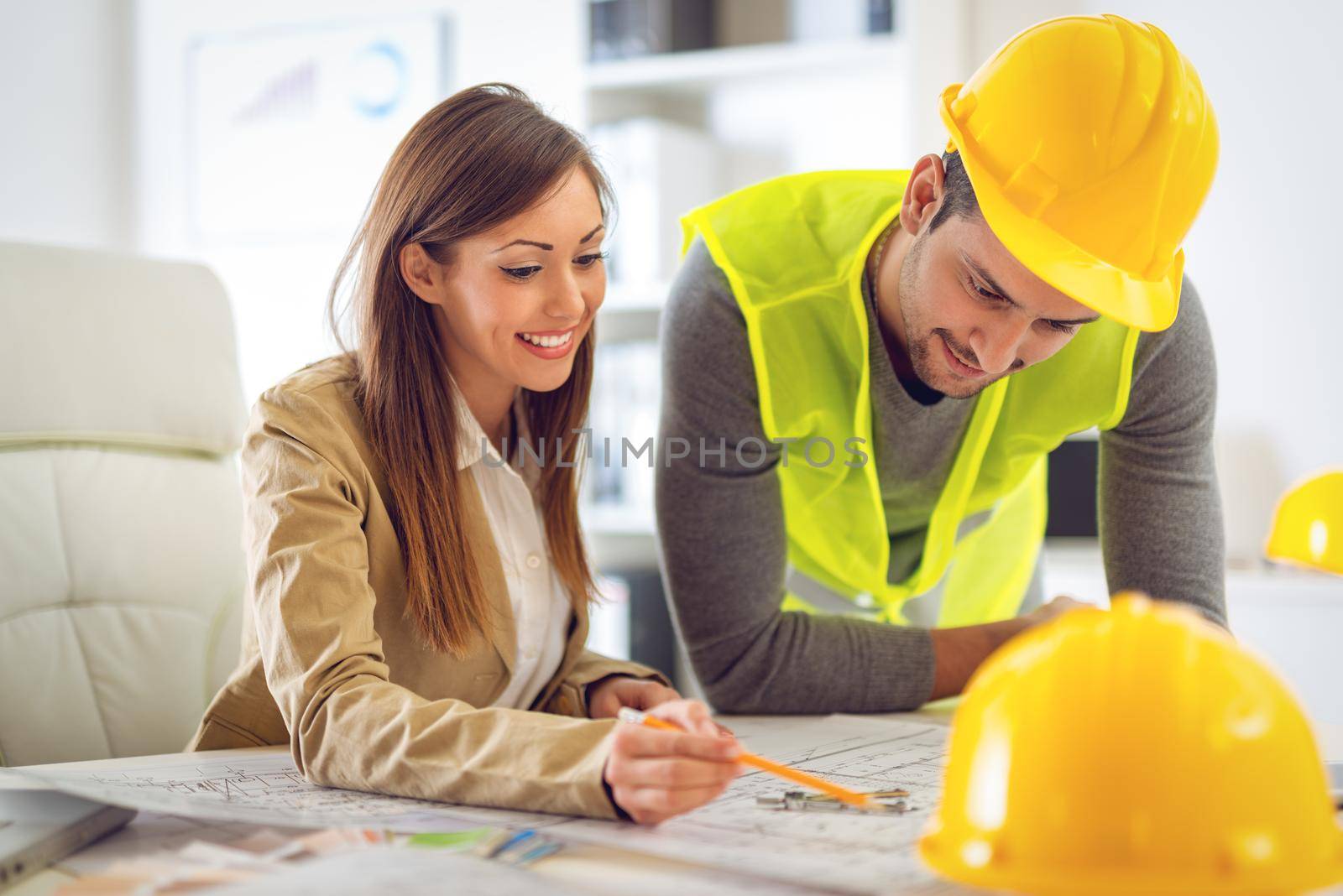 Successful young architects discussing construction plans and planning what to change to be better. They are in the office.