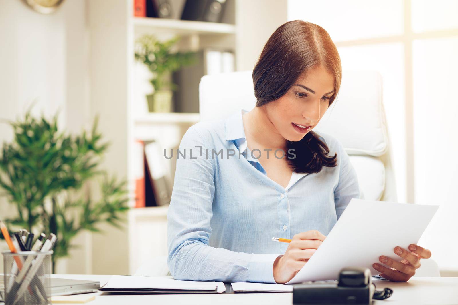 Successful young woman in the office brainstorming over business report.
