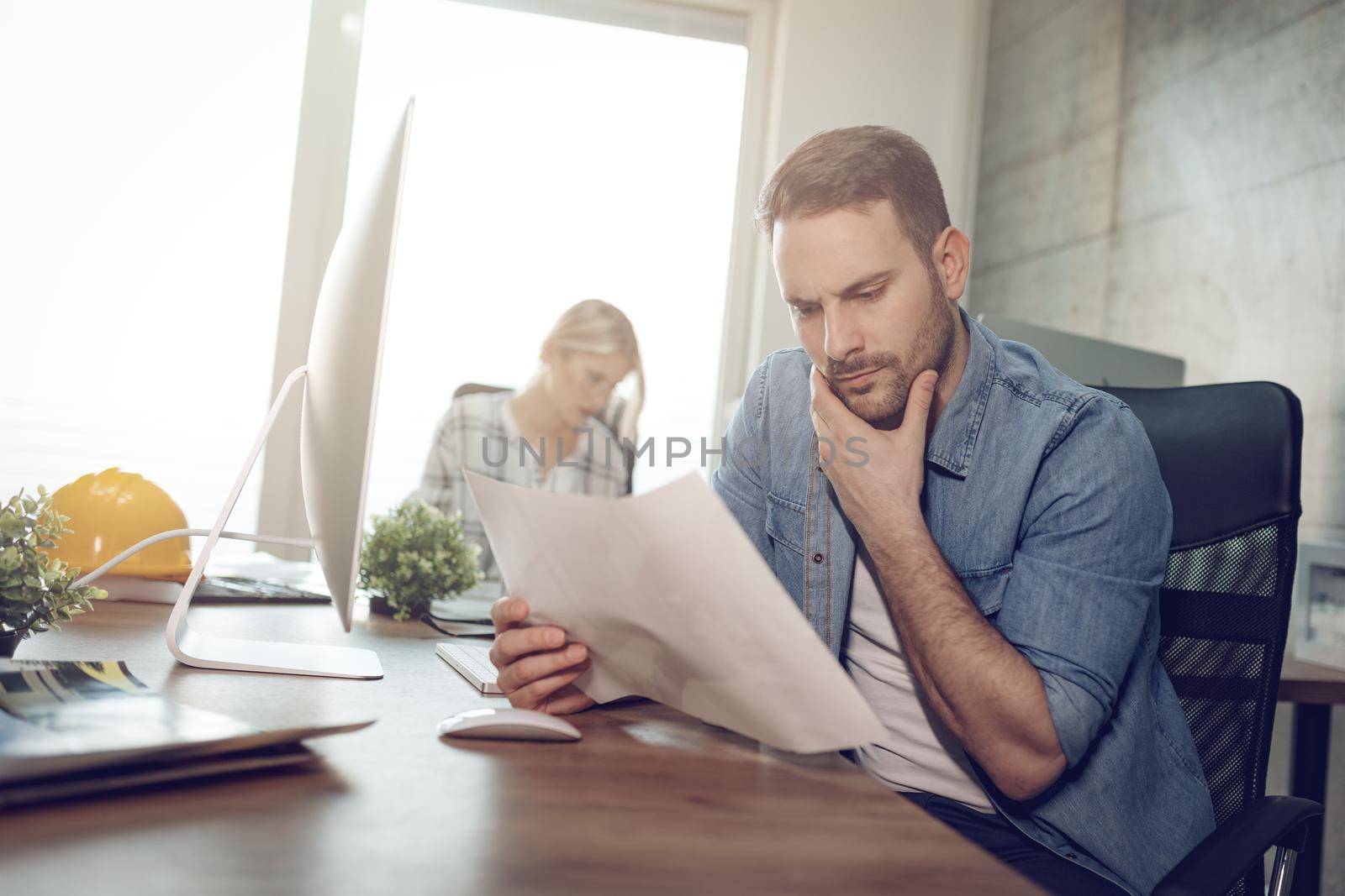 Young handsome serious pensive entrepreneur working at the office. They are looking at document and thinking abaut solving problem.