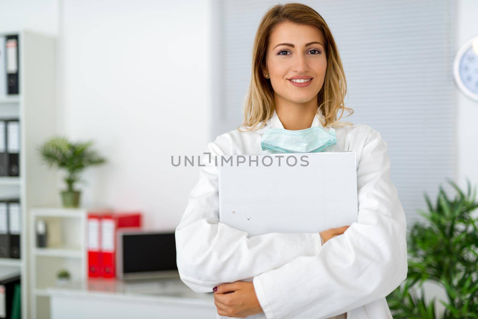 Confident female surgeon holding medical records in clinic office.