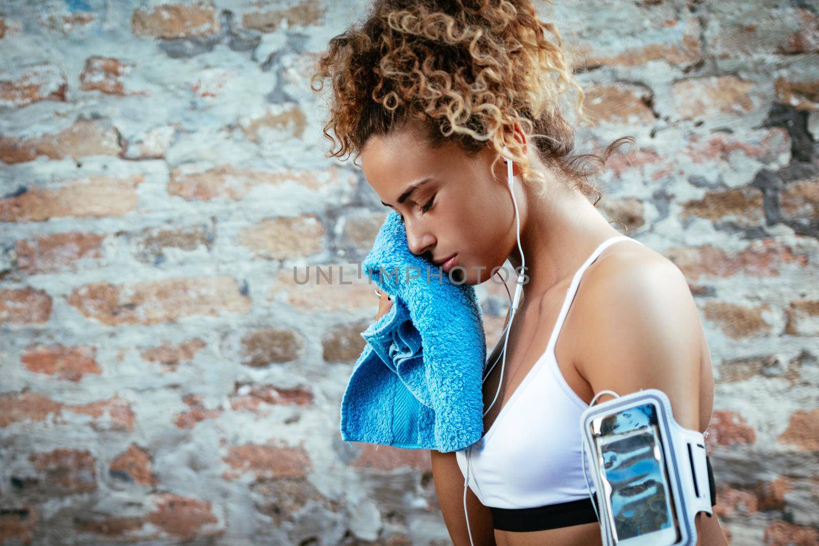 Young muscular fitness woman with headphones resting after hard training.