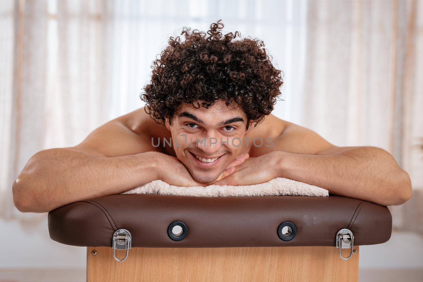 Handsome man lying down on massage table and waiting for healthy massage in spa center.