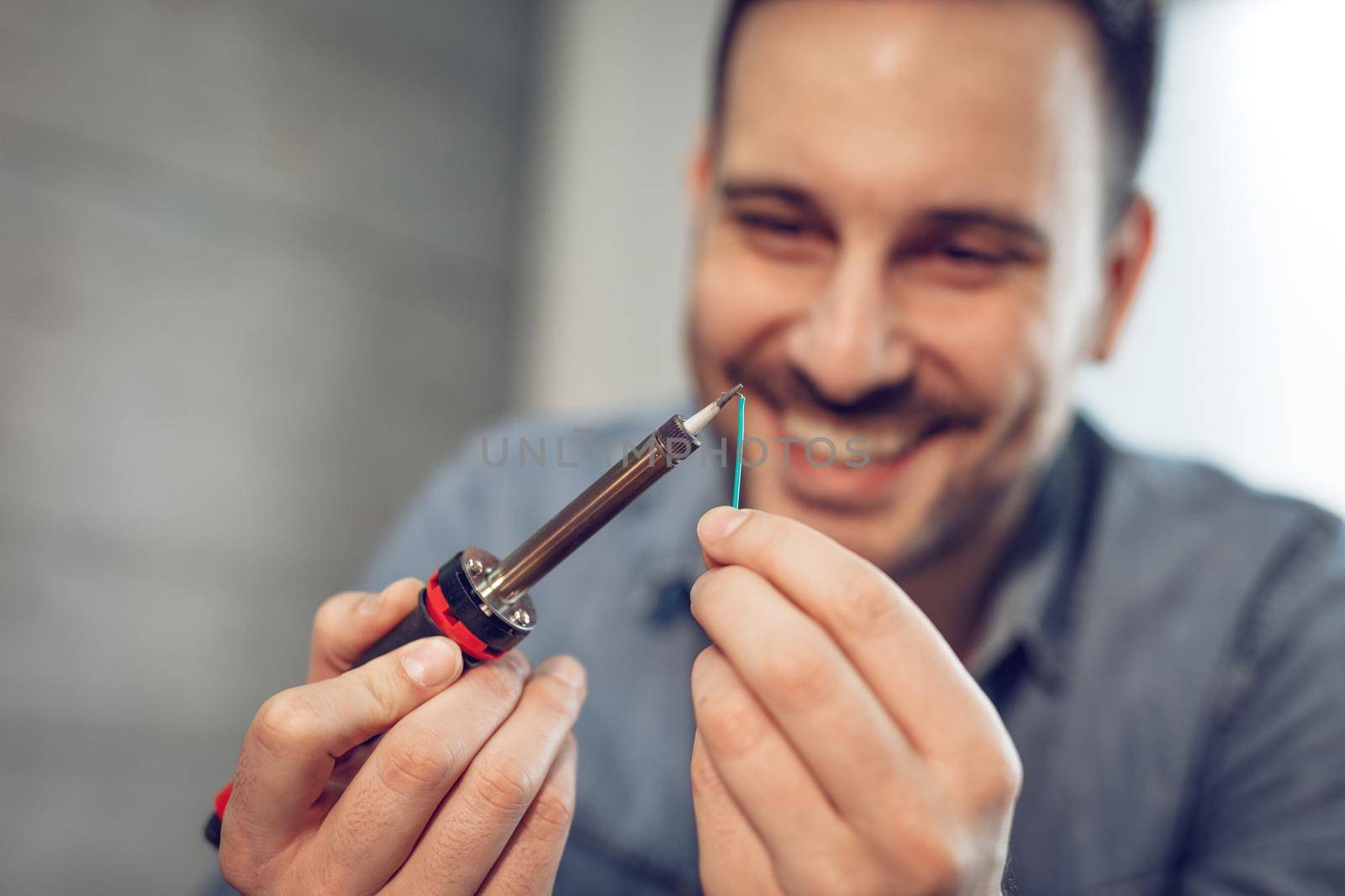 Close-up of a successful engineer or technician focused on soldering copper wire. Selective focus.