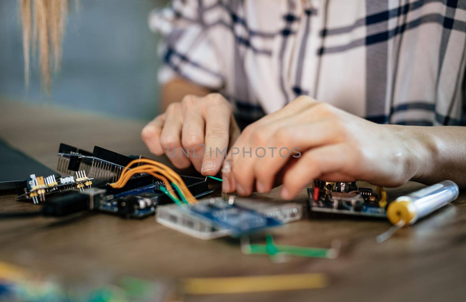 Close-up of a female hands soldering circuit board on the table.