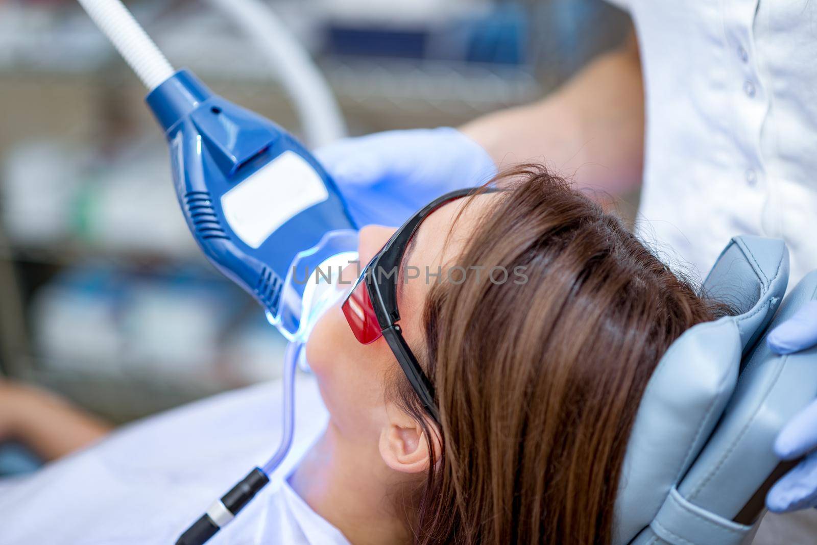 Close-up of beautiful young woman in visit at the dentist office, whitening teeth with ultraviolet light.