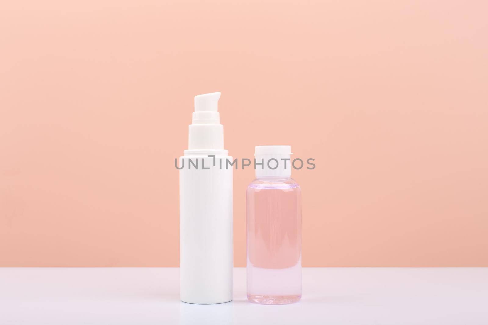 Cosmetic tubes with face cream and lotion for skin cleaning and exfoliating against bright pink background with copy space. Concept of daily skin care and beauty