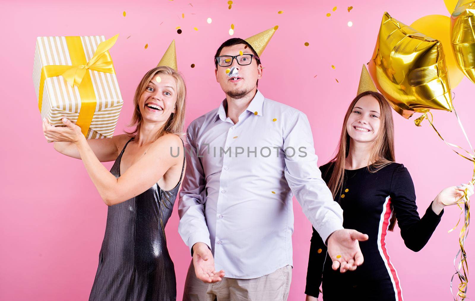 Portrait of joyful friends celebrating birthday party, pink background by Desperada