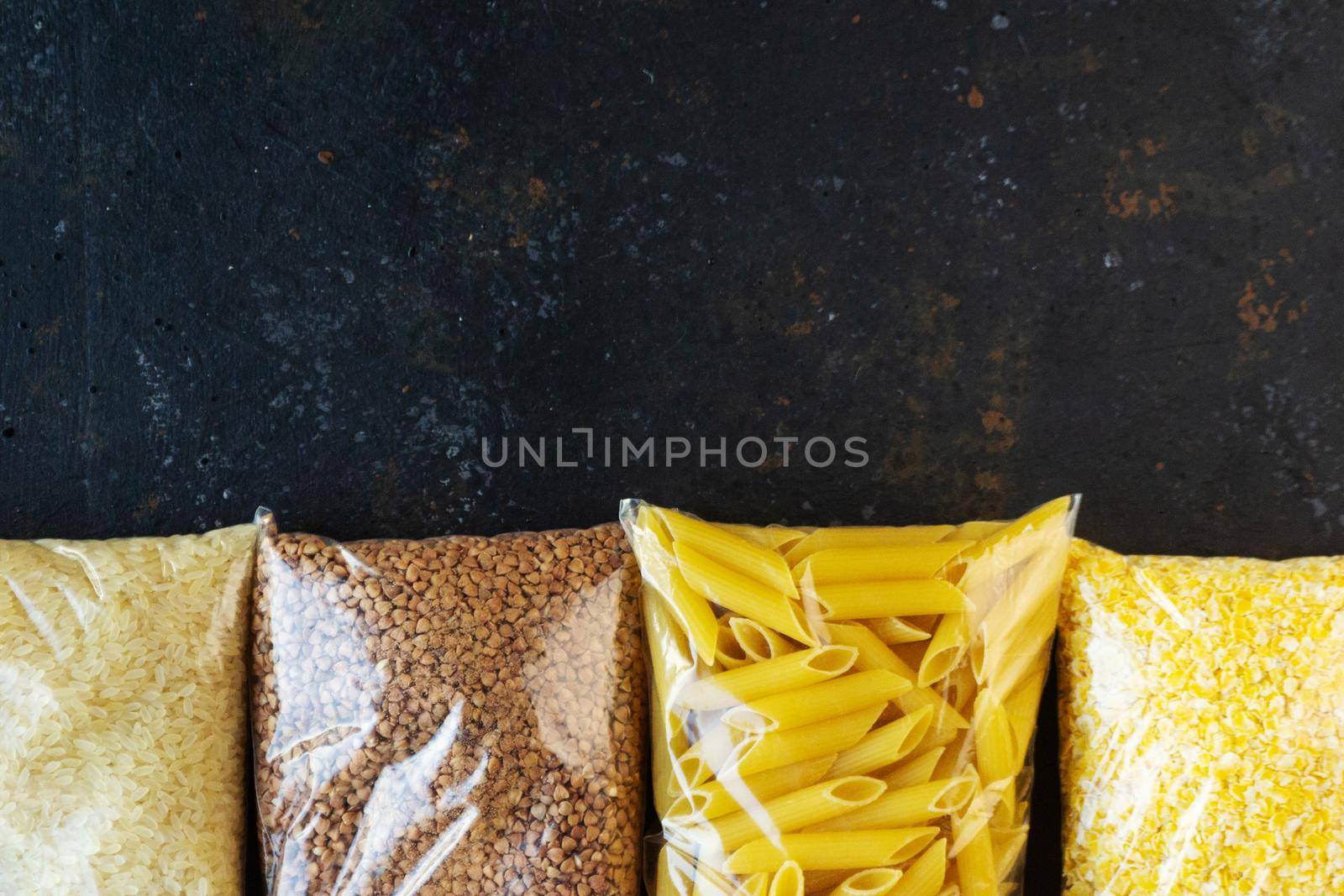 Food supply quarantine food crisis isolated on black concrete background. Rice, pasta, corn flakes, buckwheat. The concept of food delivery, donation, charity. Copyspace.