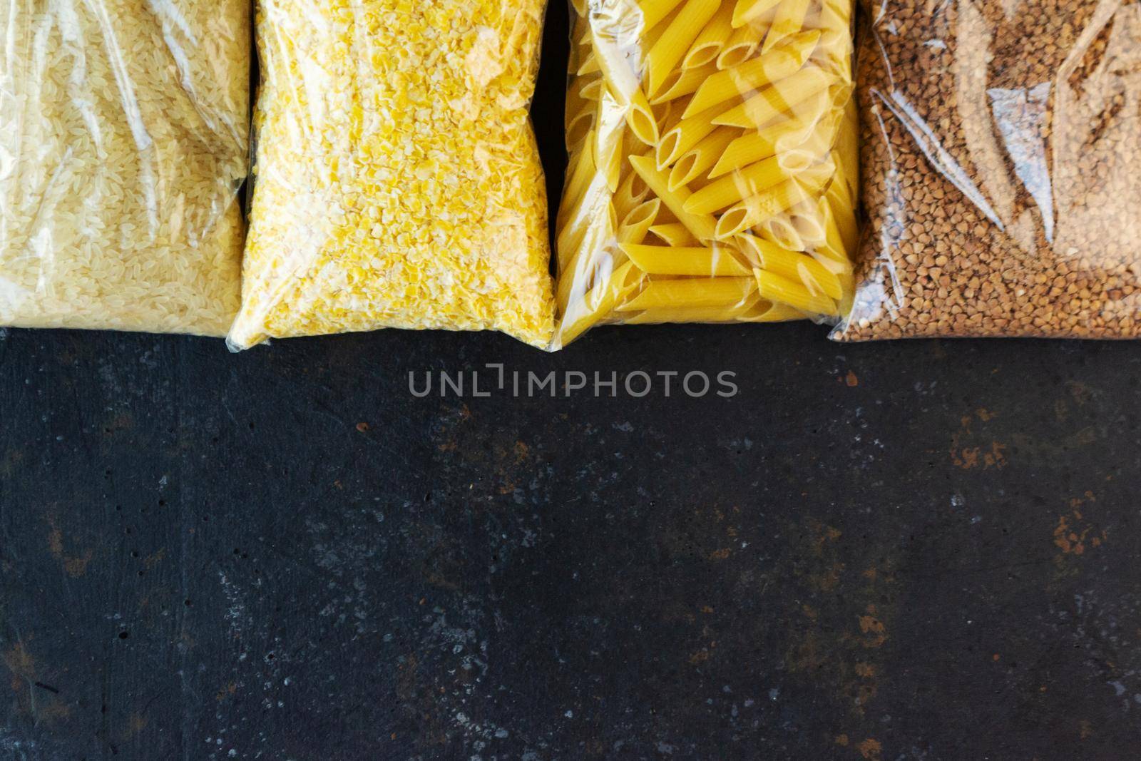 Food supply quarantine food crisis isolated on black concrete background. Rice, pasta, corn flakes, buckwheat. The concept of food delivery, donation, charity. Copyspace.