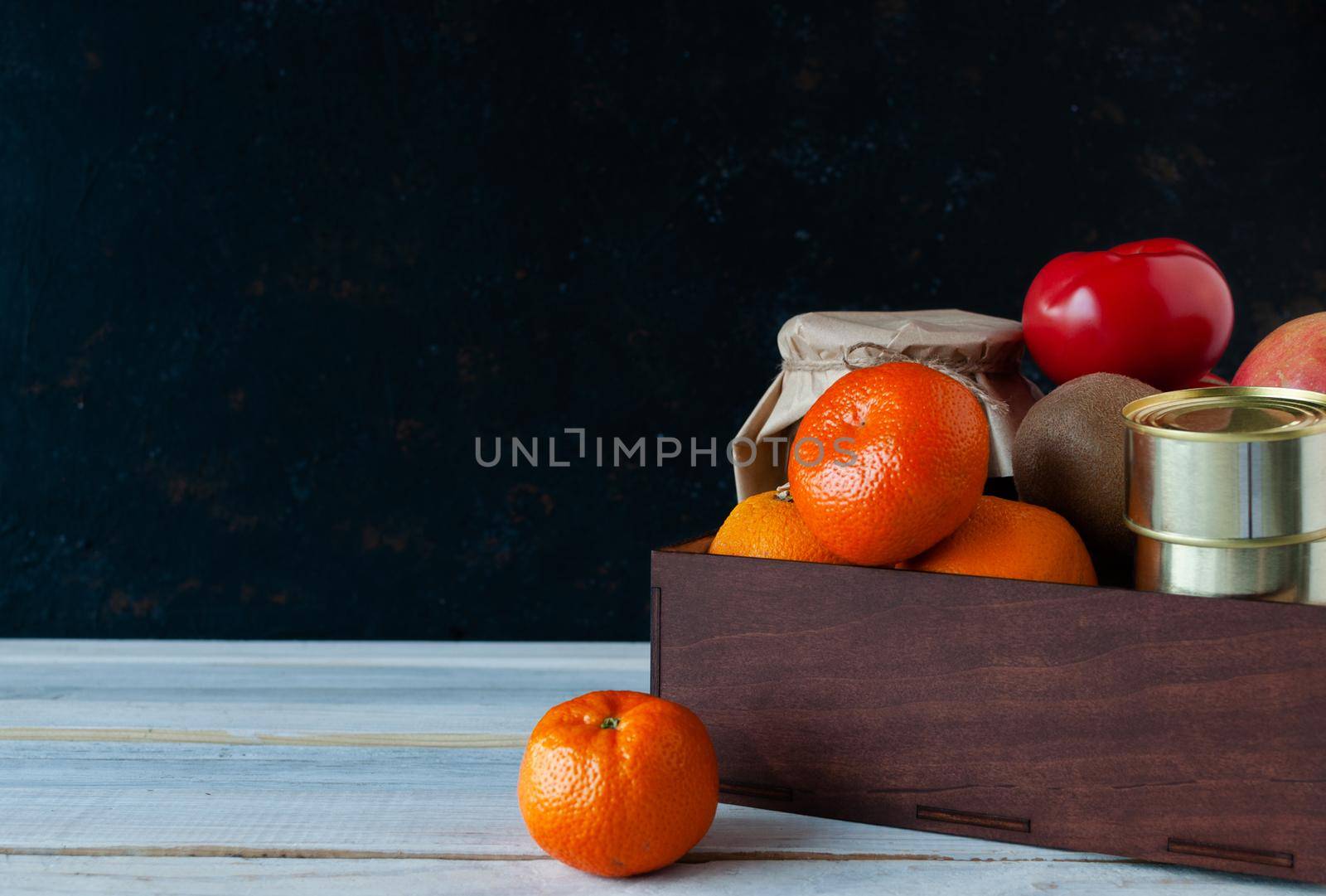 Food delivery during quarantine and isolation. Products folded in a box on a wooden white table background. Fruits vegetables, canned goods, cereals. Concept of donation and mercy. Copy space.