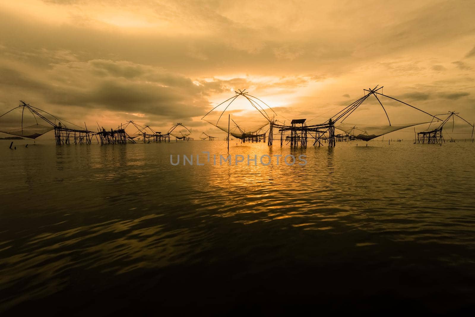 Beautiful nature landscape colorful golden light of the morning sky at sunrise and native fishing tool rural lifestyle at Pakpra canal, Songkhla Lake, Baan Pak Pra, landmark of Phatthalung, Thailand