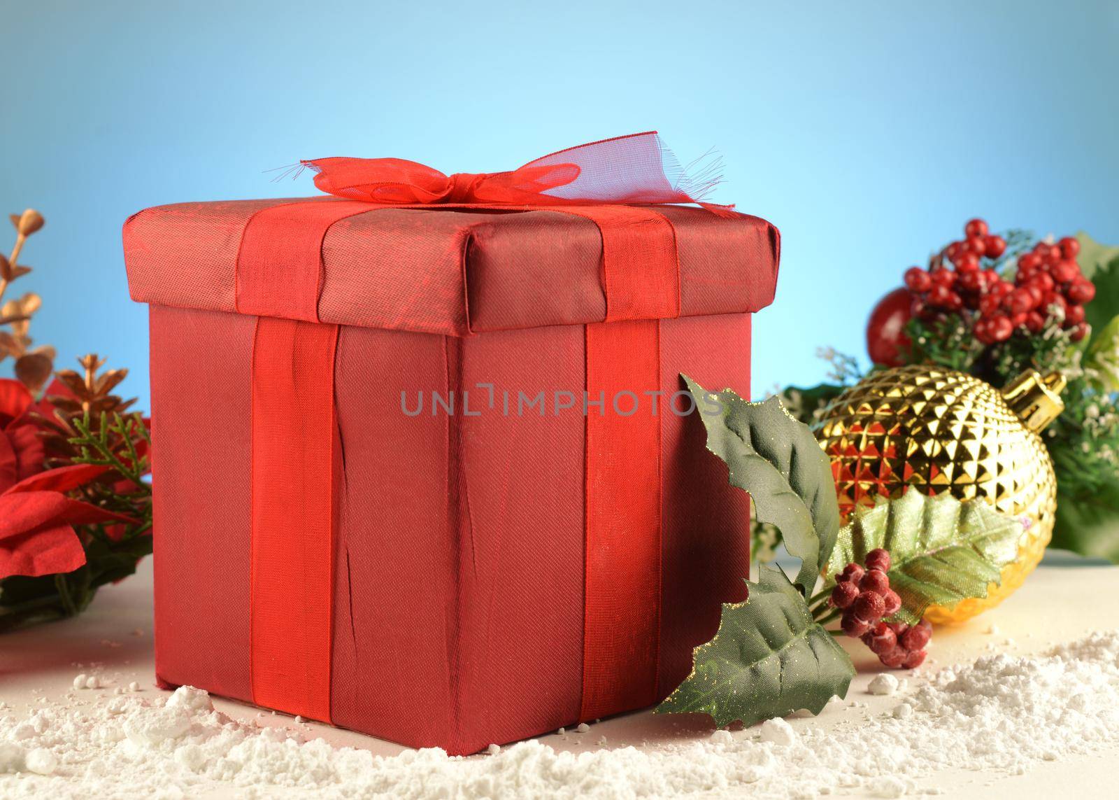 A red gift box and bow set inside a festive scene for the Christmas holiday season of gift giving.