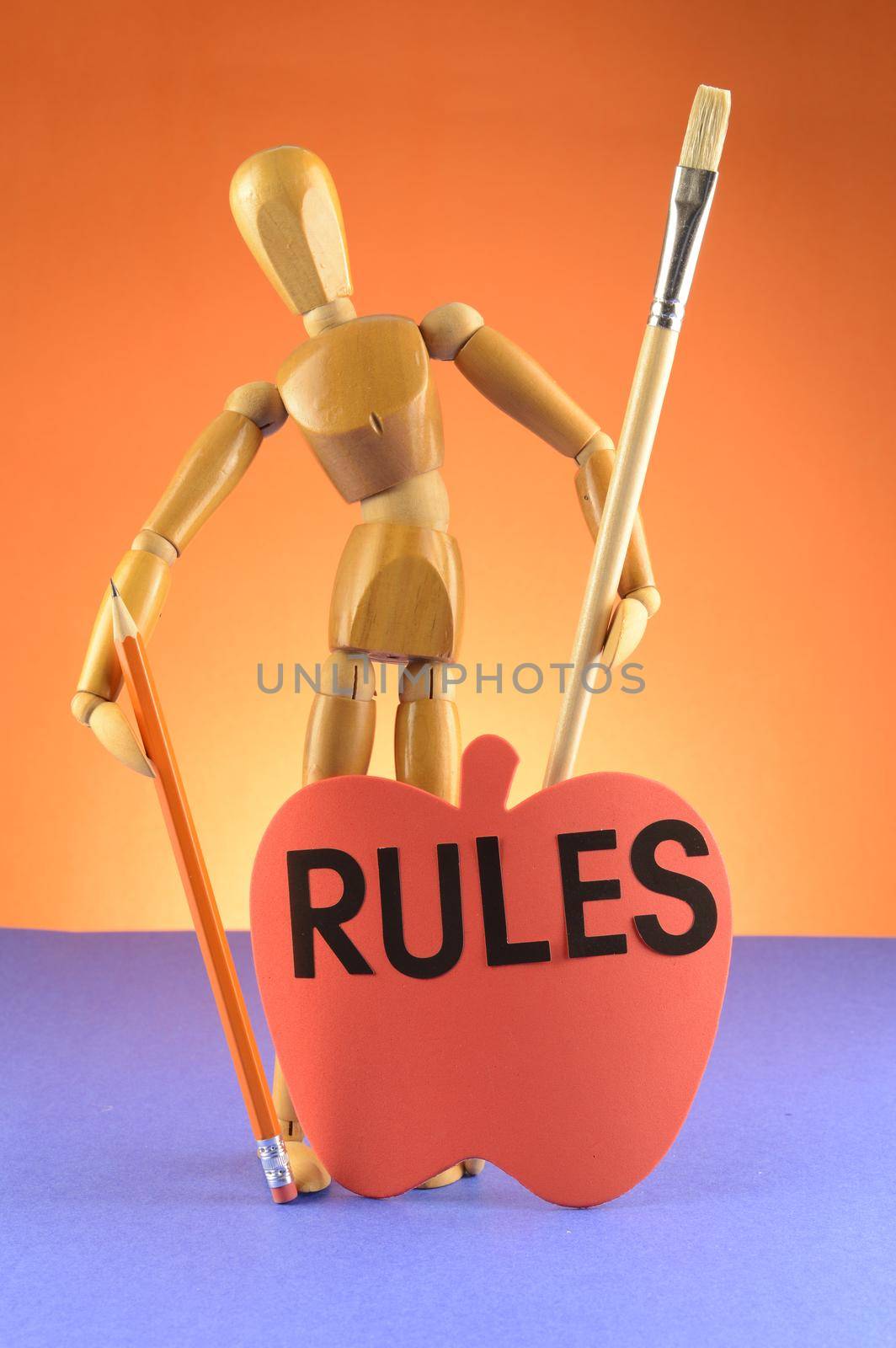 An Artist wooden Dummy Mannequin showcases the importance of rules in the fine art world while holding a pencil and a paintbrush.