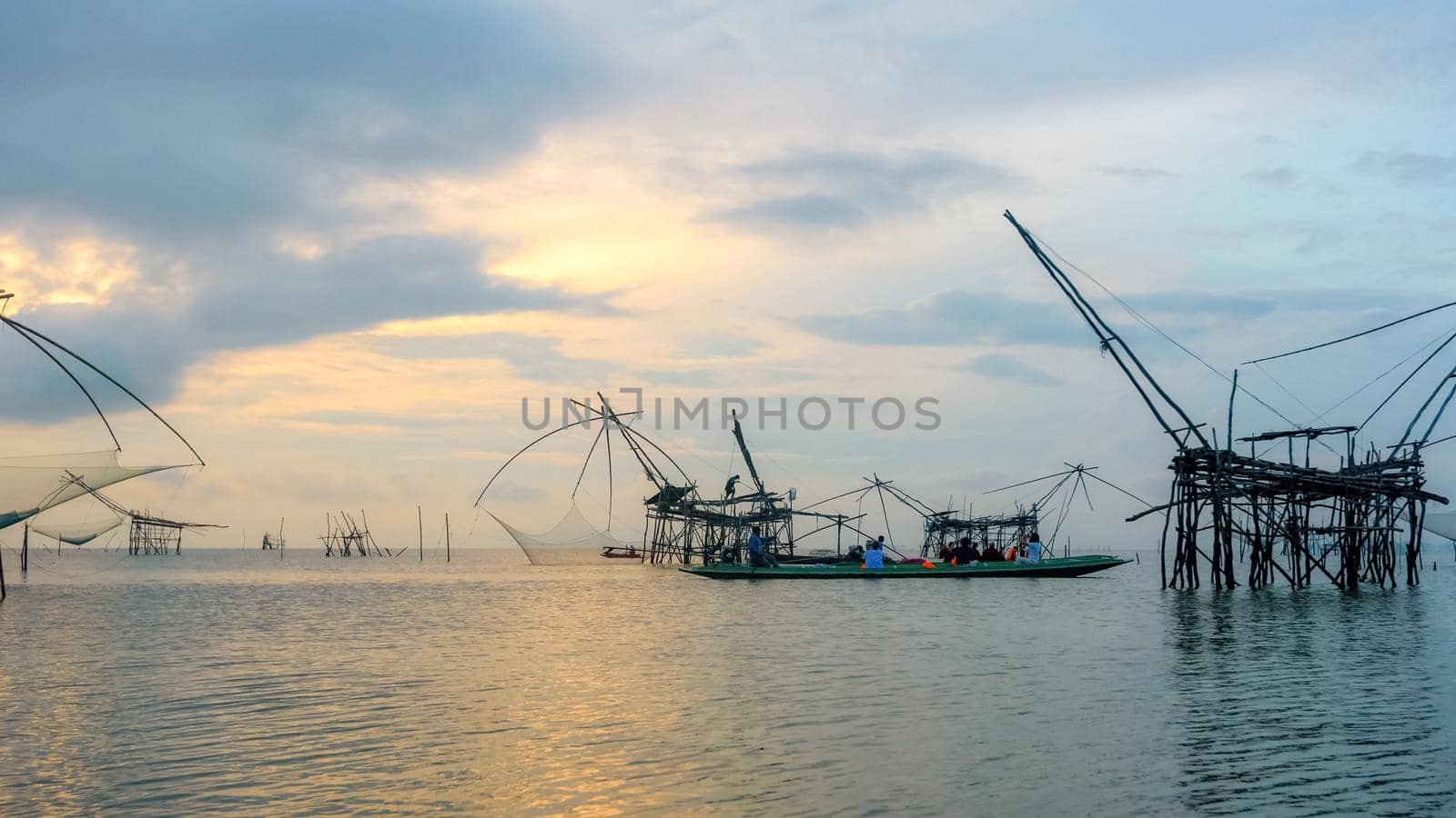 PHATTHALUNG, THAILAND-APRIL 27, 2018: Tourist group travel by boat to see fisherman are using bamboo and net as native fishing tool during sunrise, rural lifestyle at Pakpra canal in Songkhla Lake