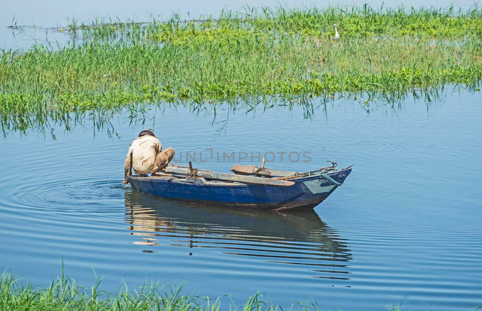 Traditional egyptian bedouin fisherman in rowing boat on river Nile fishing by riverbank