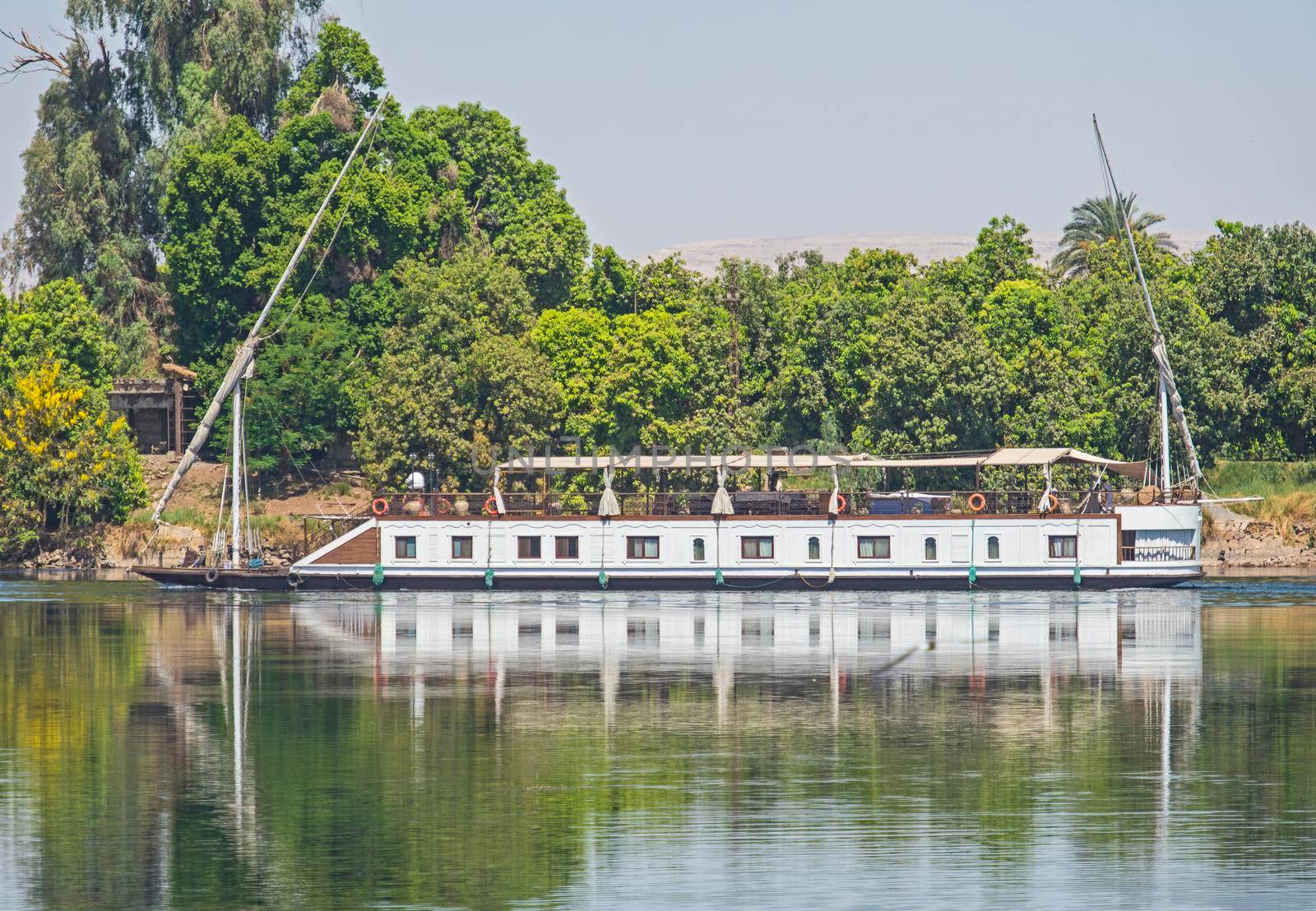 Large luxury traditional Egyptian dahabeya river cruise boat moored on the Nile bank