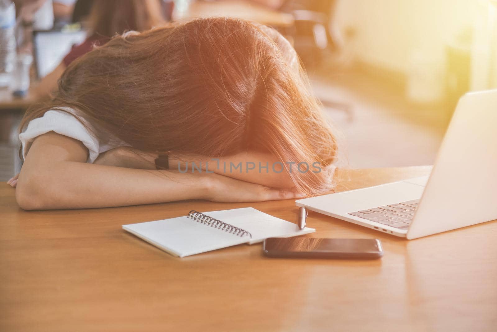 Tired woman sleeping on her desk  by NuwatPhoto