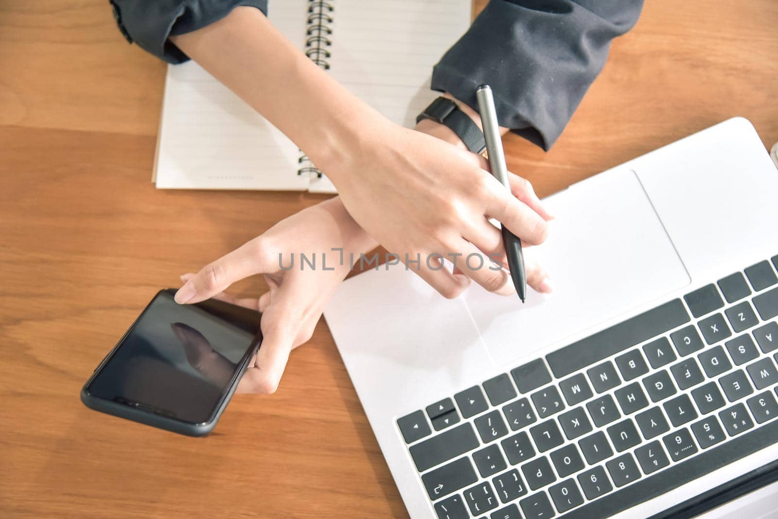 Young businesswoman using smart phone on her desk at the workplace, closeup
