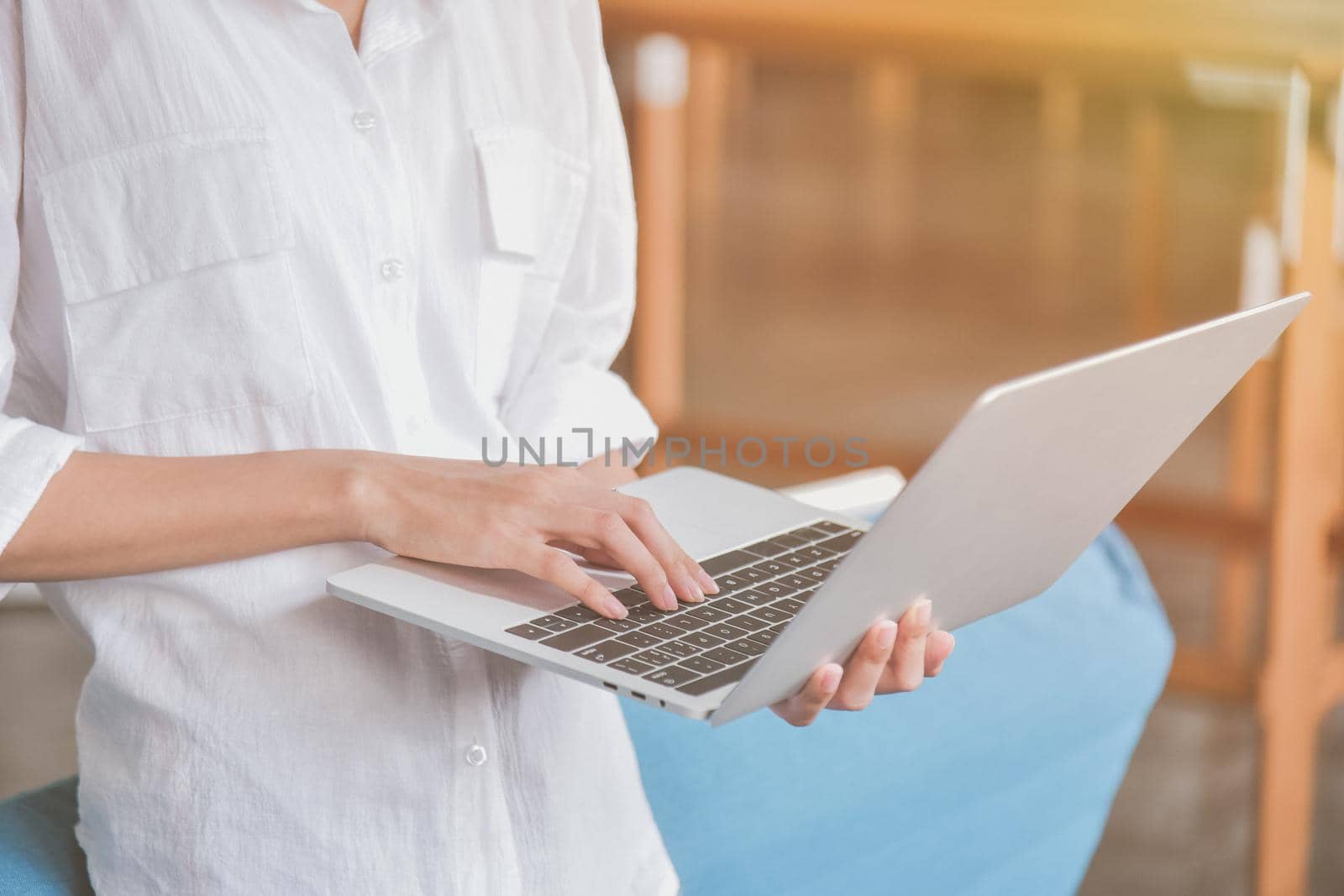 Young woman useing and holding silver laptop at the workplace, closeup